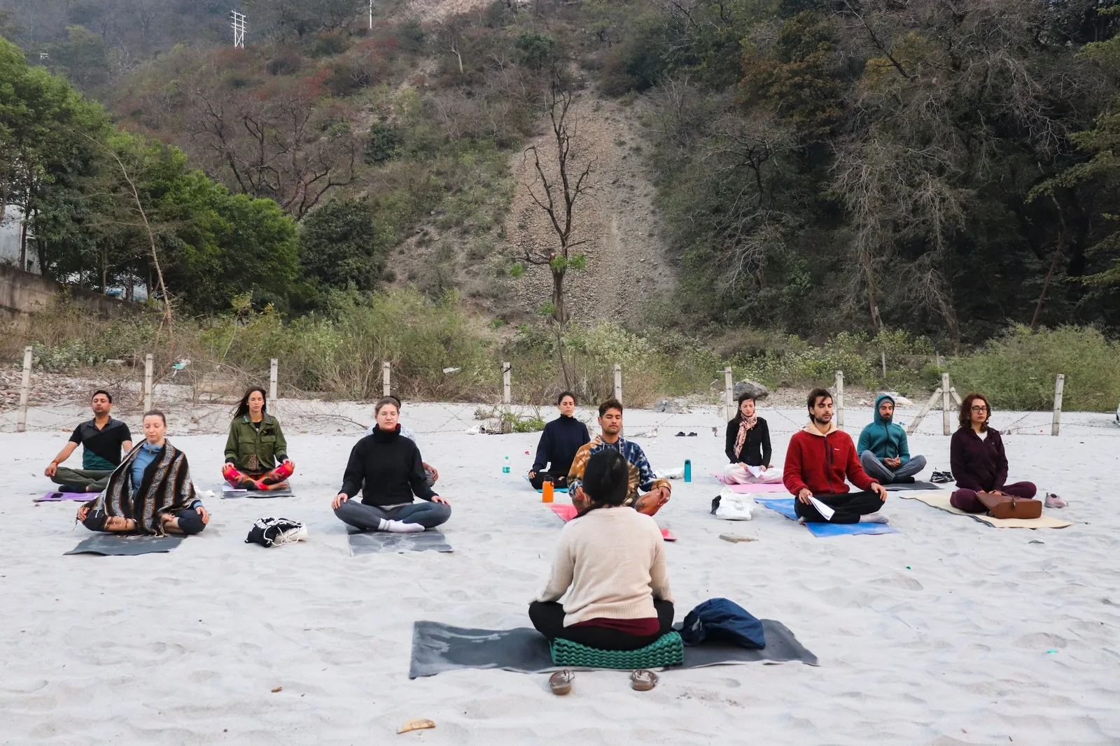 A group meditating on the sand beside the Ganga, Rishikesh