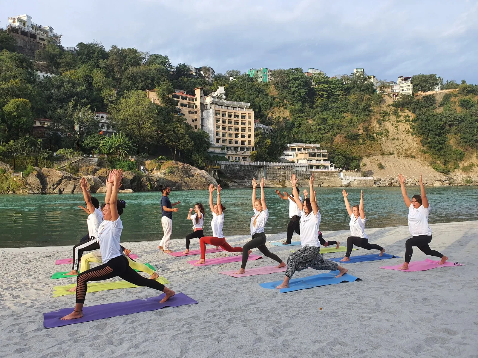 A class in the warrior pose on the sand beside the Ganga, Rishikesh
