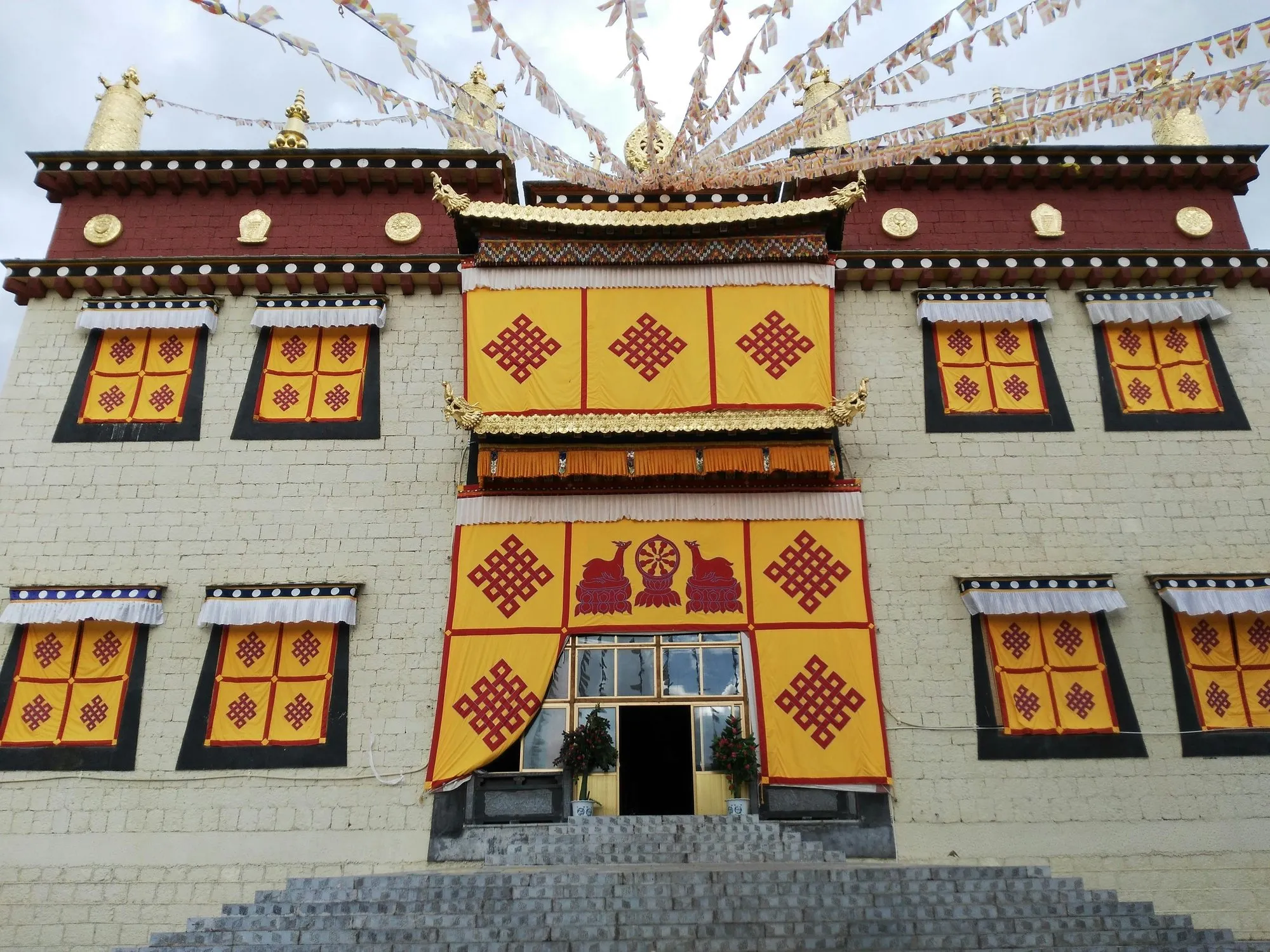 A monastery front with yellow-framed windows and prayer flags