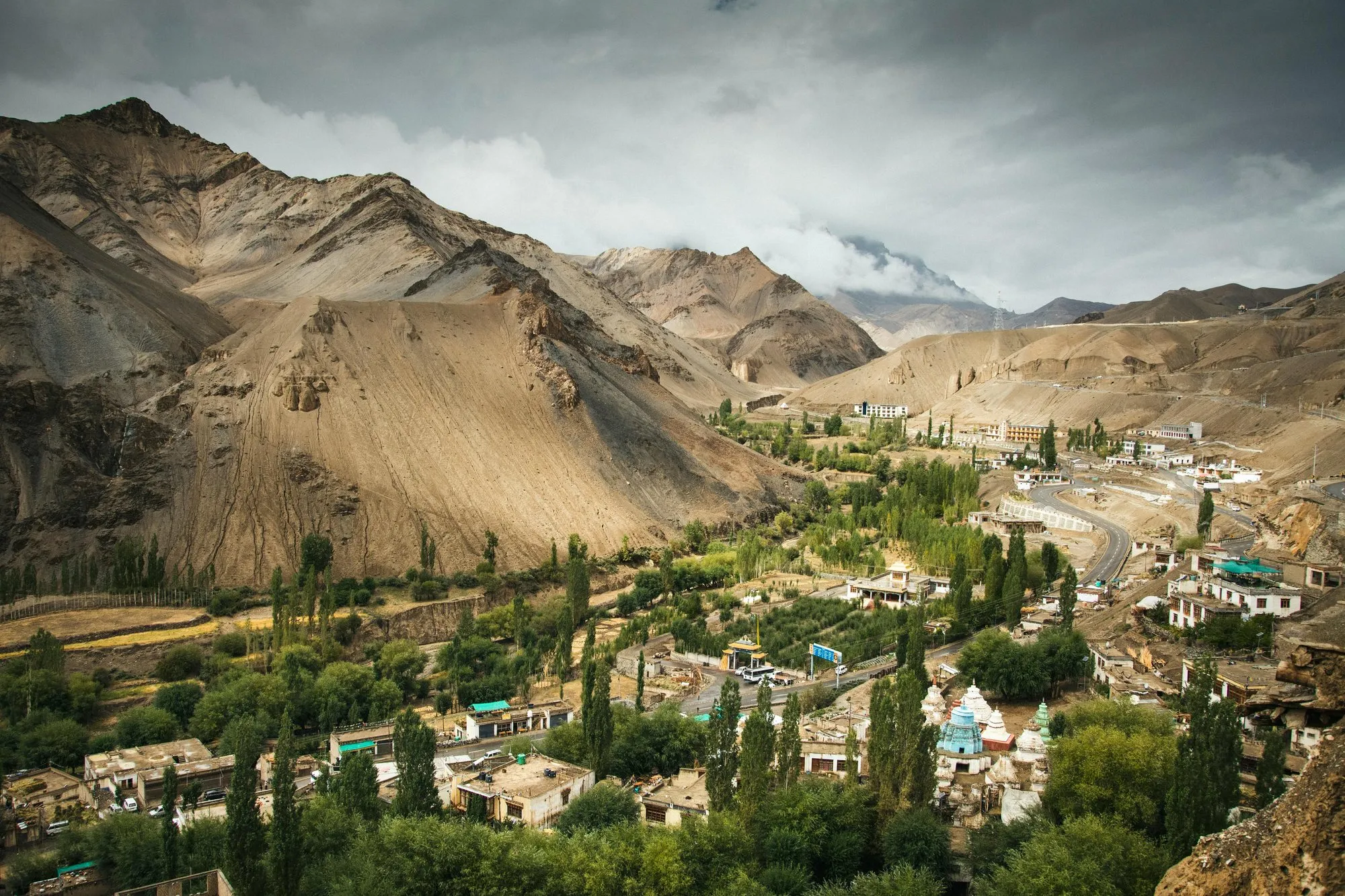 A green valley village between bare mountains