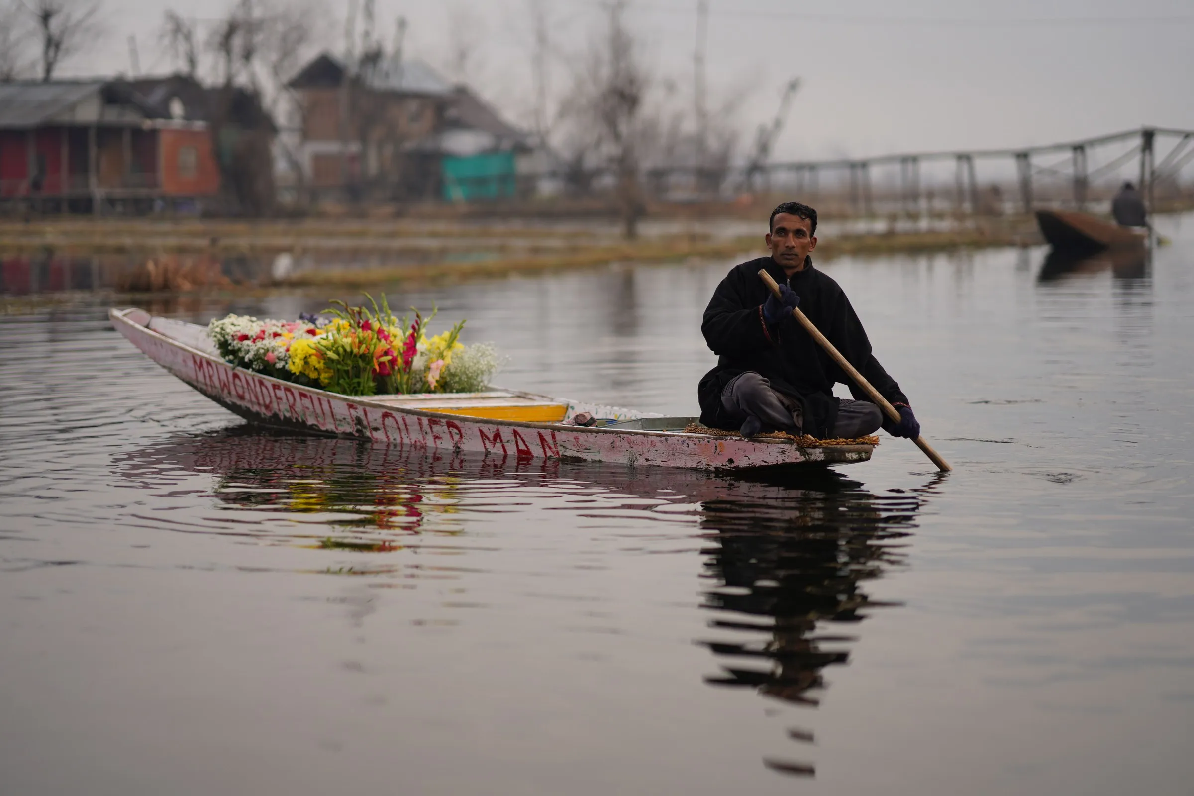 A flower seller paddling his boat, heaped with blooms, across Dal Lake, Srinagar