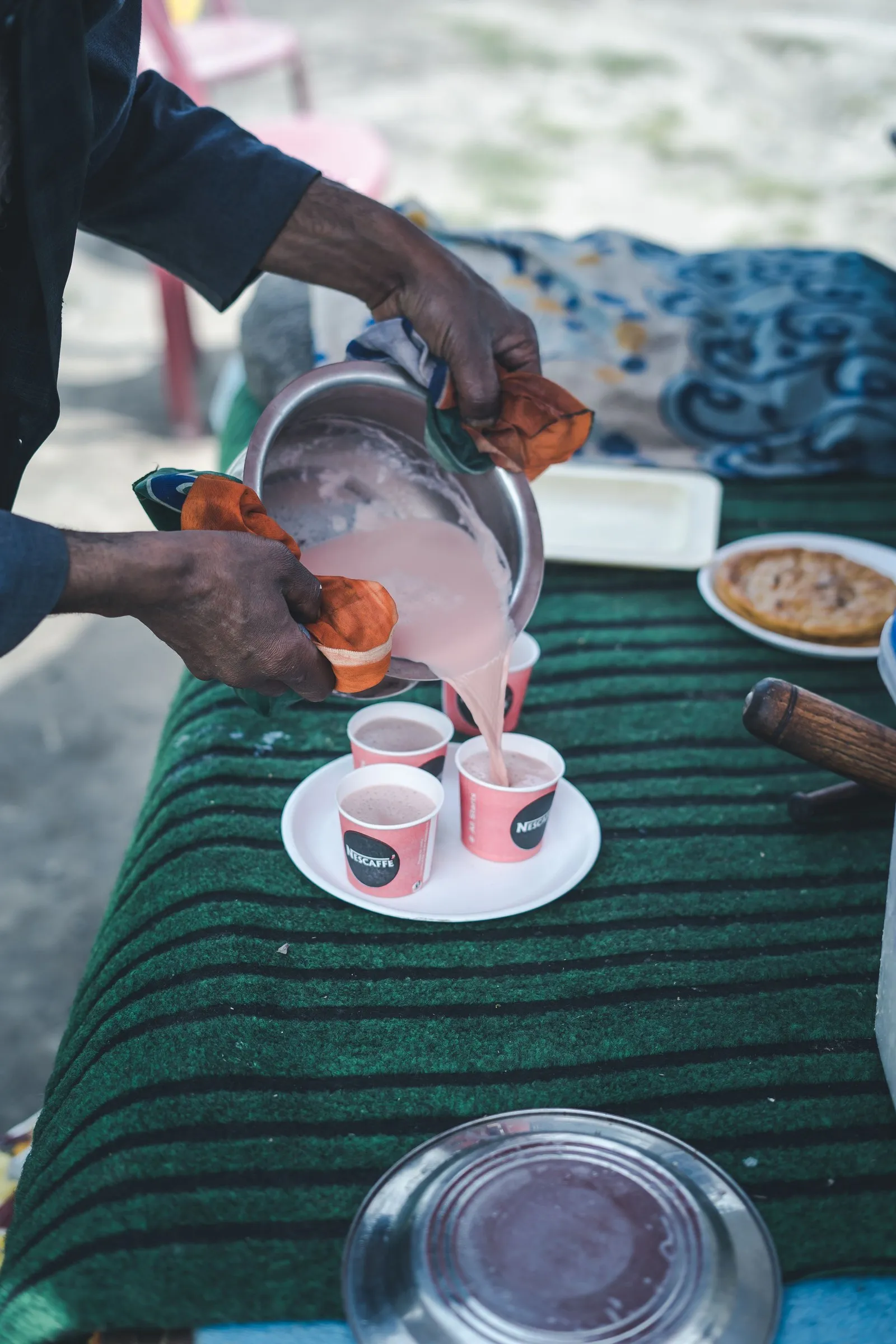 Kahwa poured from a brass pot into small cups at a stall in Srinagar
