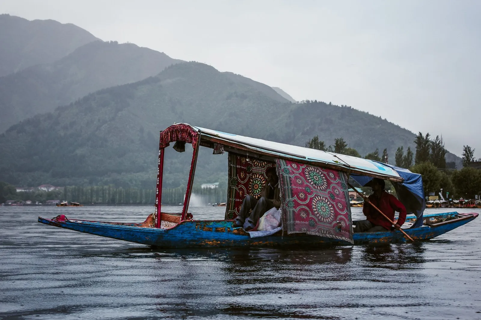 A shikara with embroidered curtains on Dal Lake on a misty morning