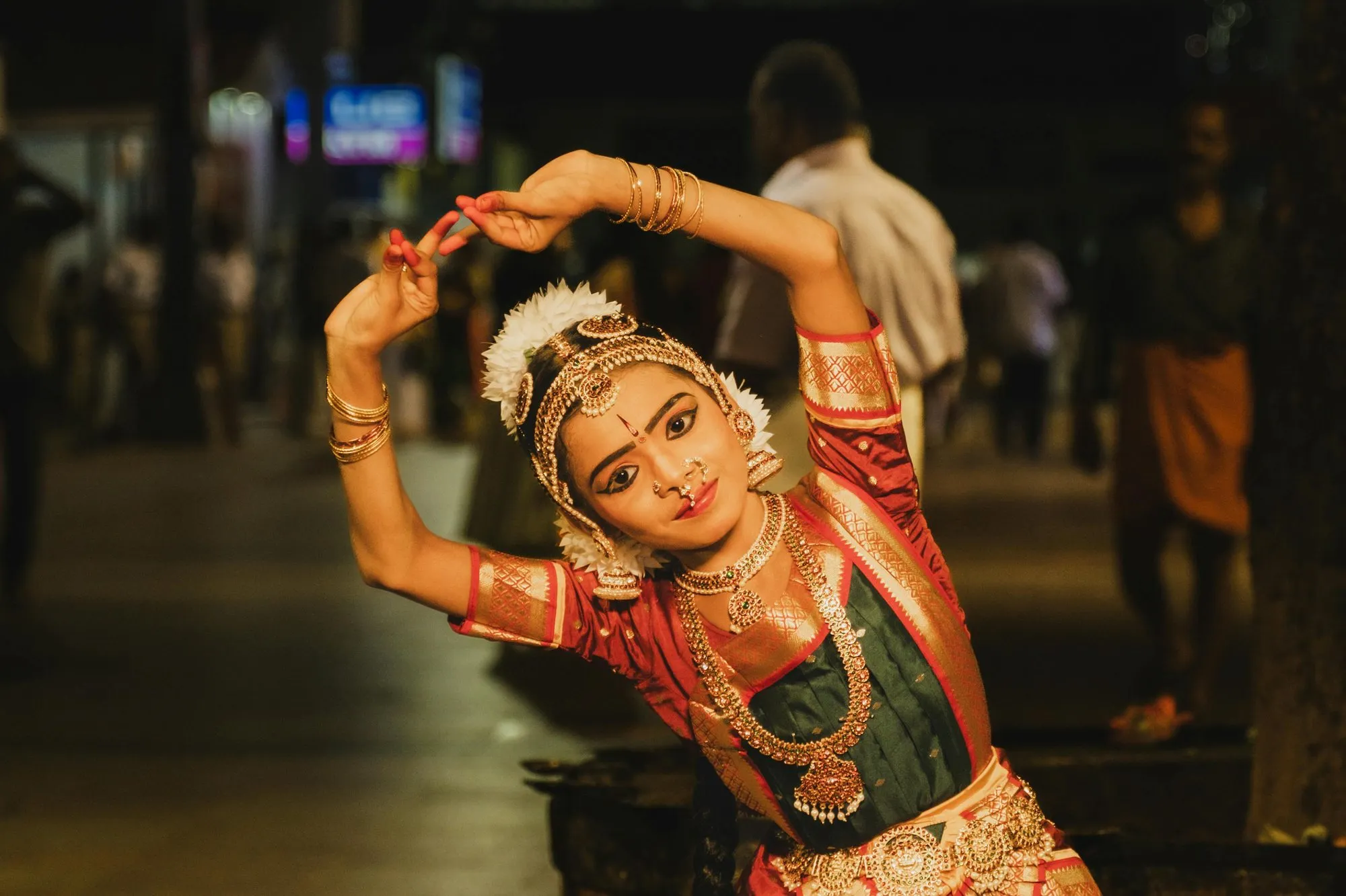 A young classical dancer in temple jewellery, arms raised