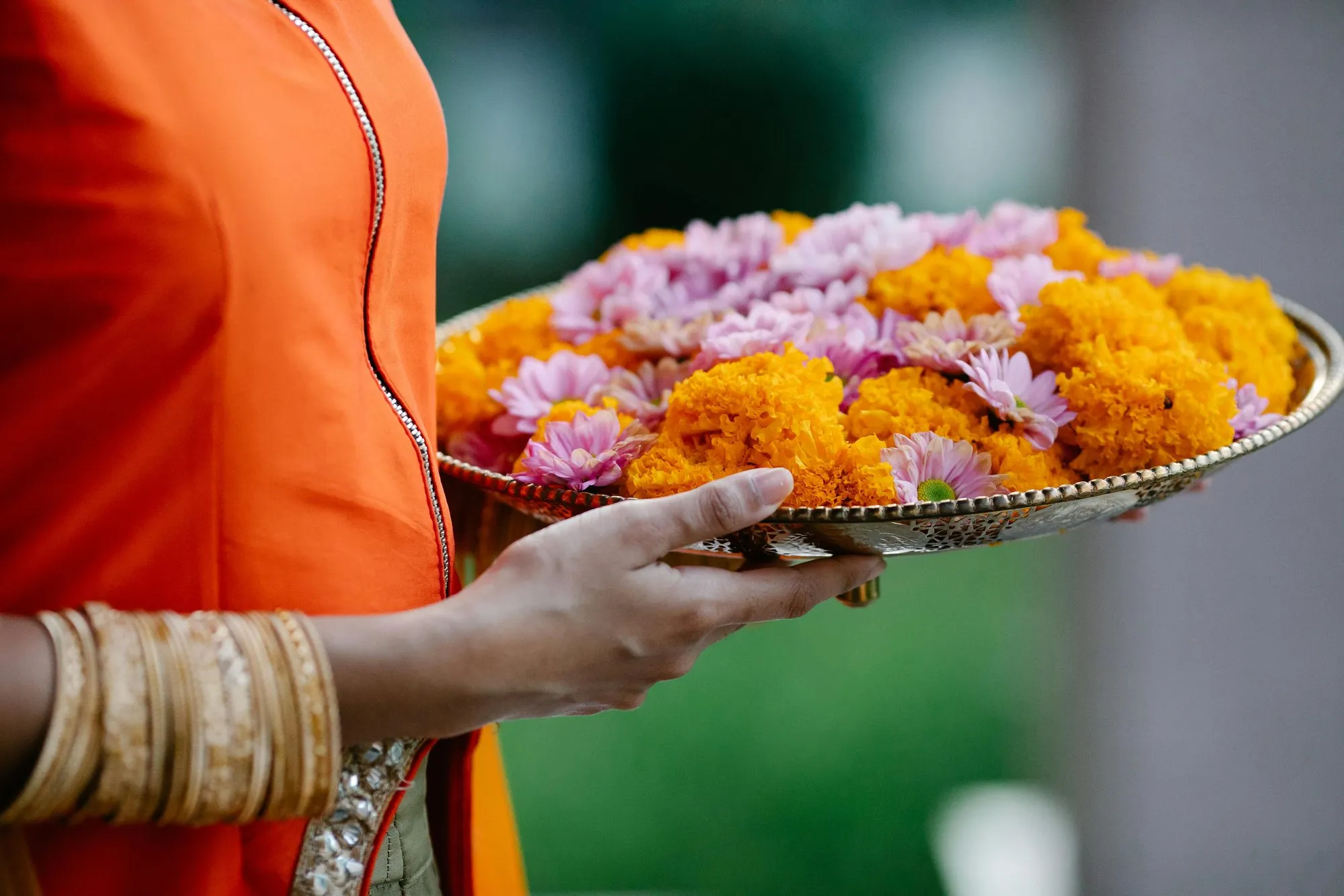 A brass plate of marigolds and flowers held in both hands