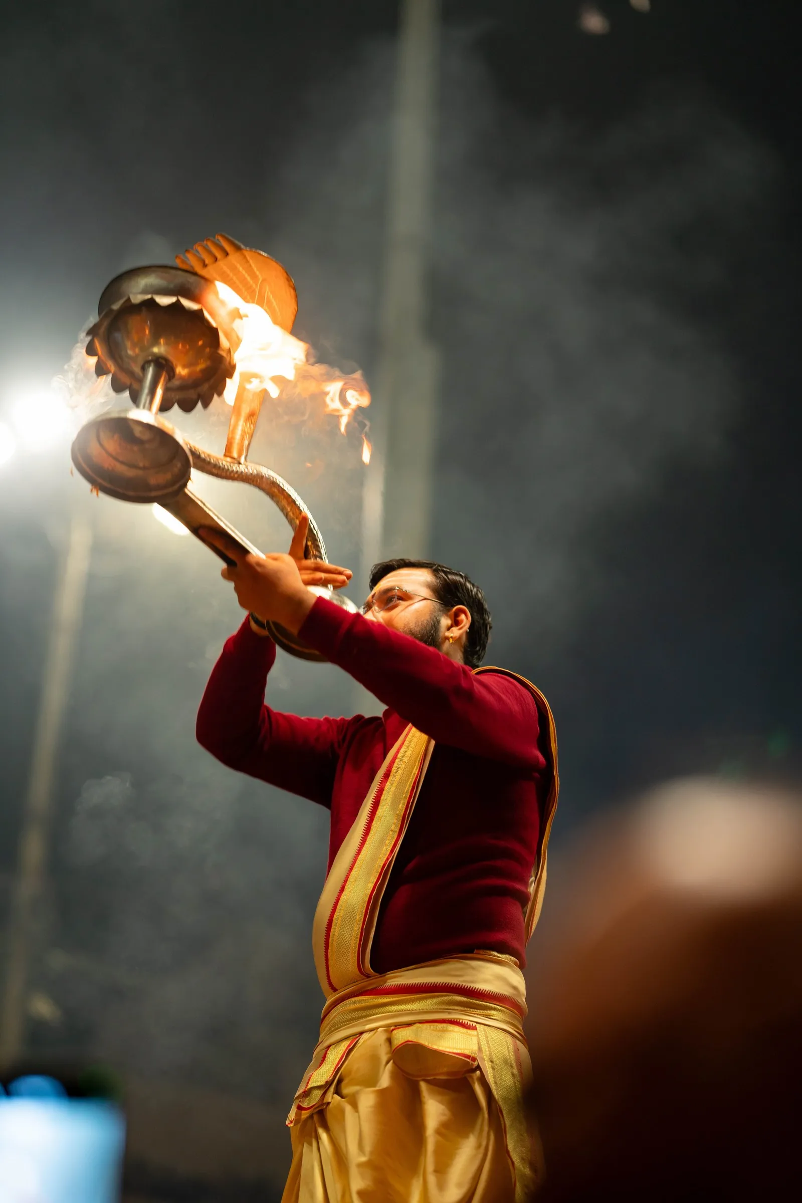 A priest raising a flaming lamp at the evening aarti, Kumbh Mela, Prayagraj