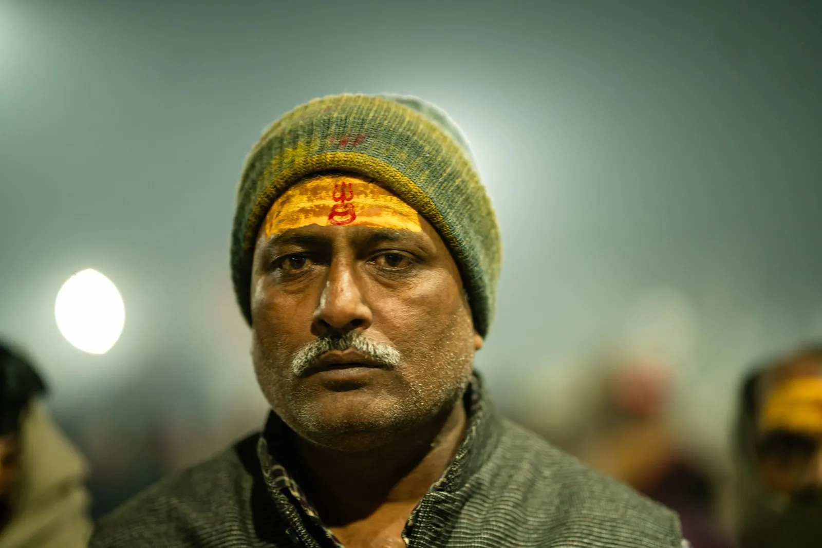A pilgrim in a woollen cap with a tilak on his forehead, at the Kumbh Mela