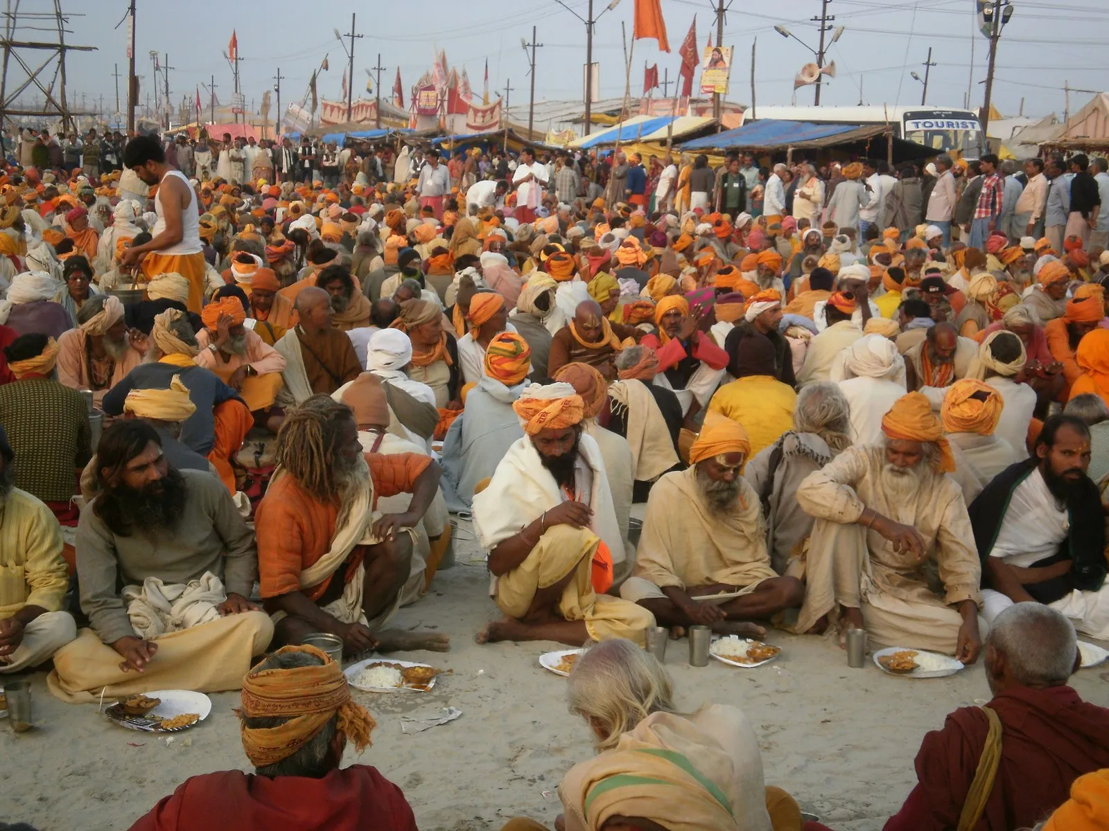 Sadhus and pilgrims sitting down to a shared meal on the ground at the Kumbh Mela