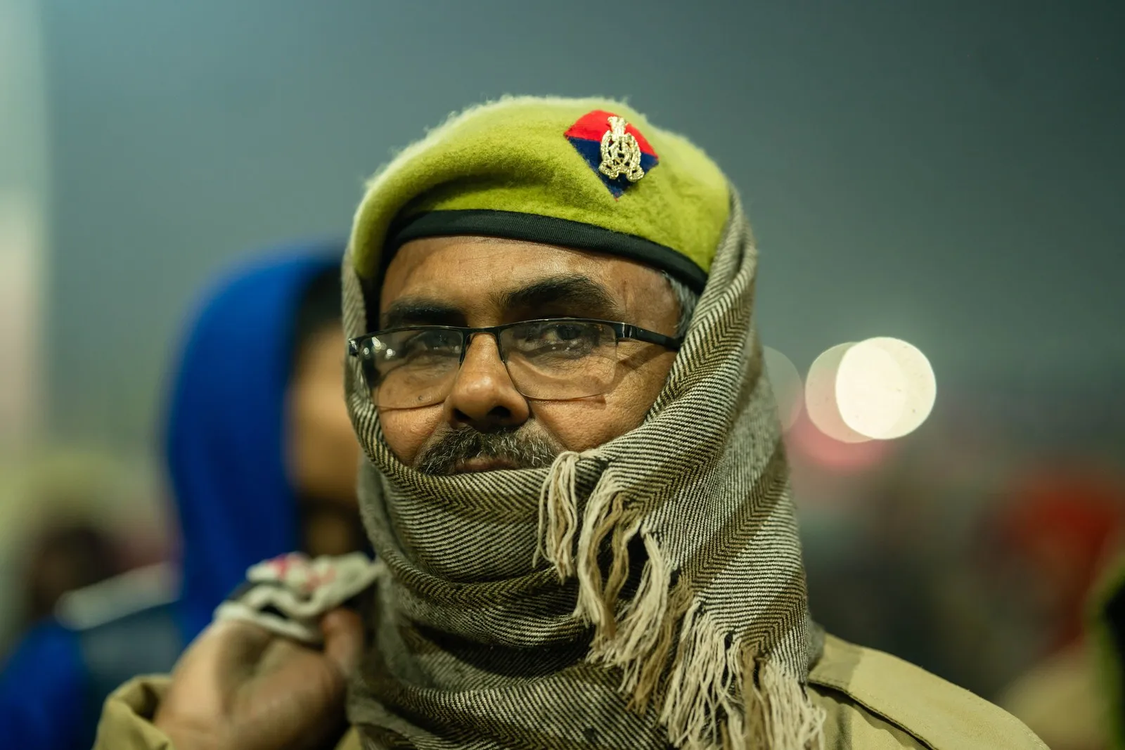 A police officer wrapped against the January cold, on duty at night at the Mela