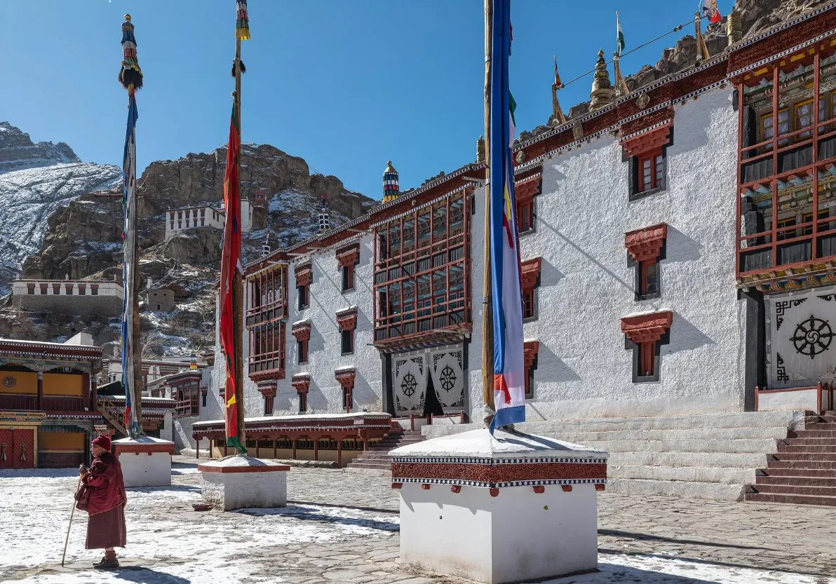 A monastery courtyard with snow and prayer flags