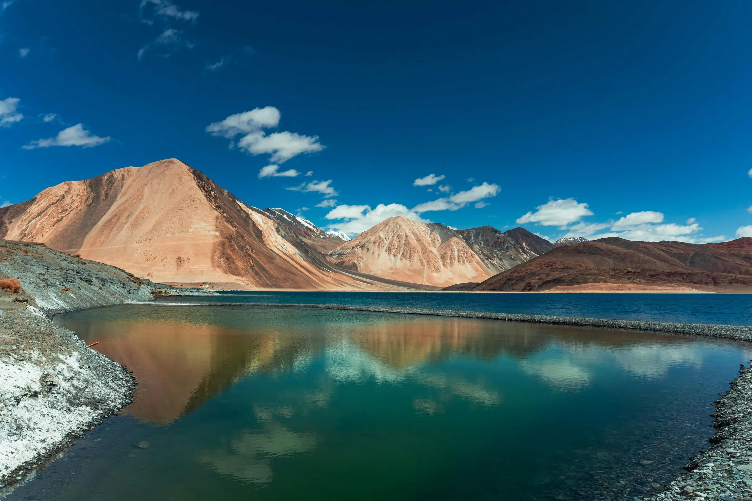 Pangong Lake, turquoise below bare mountains and white clouds