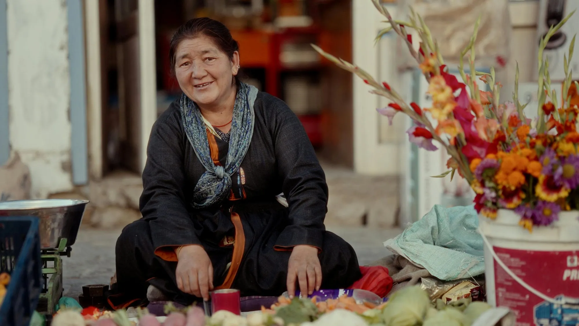 A woman selling flowers and vegetables from her stall