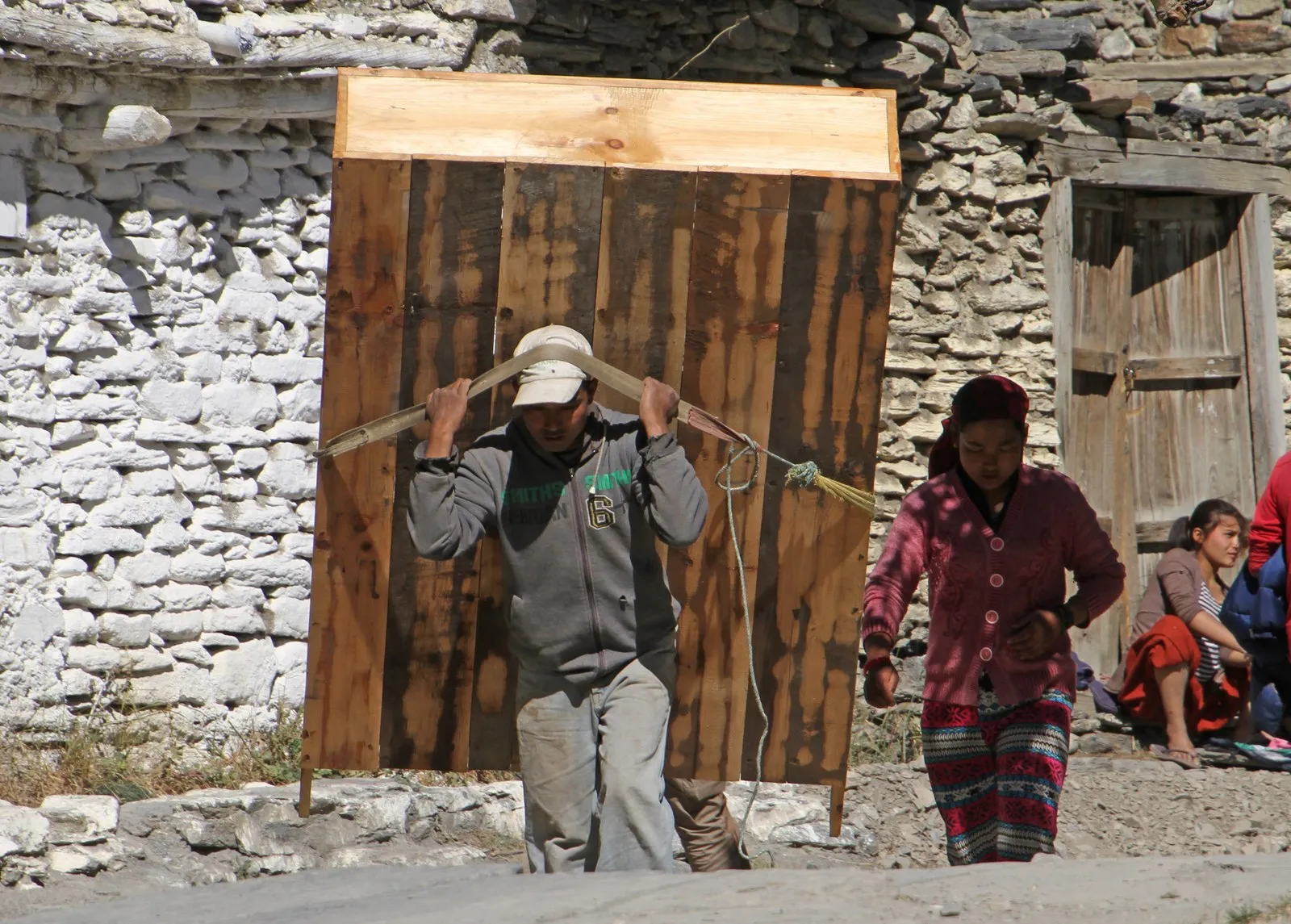 A man carrying a wooden cupboard on his back through the lanes of Marpha, Mustang