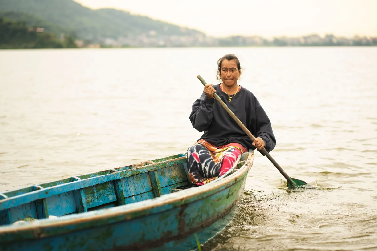 A woman paddling a wooden boat on Phewa Lake, Pokhara