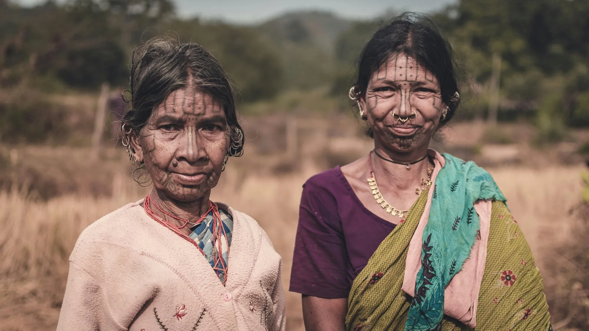 Two women with facial tattoos in a field