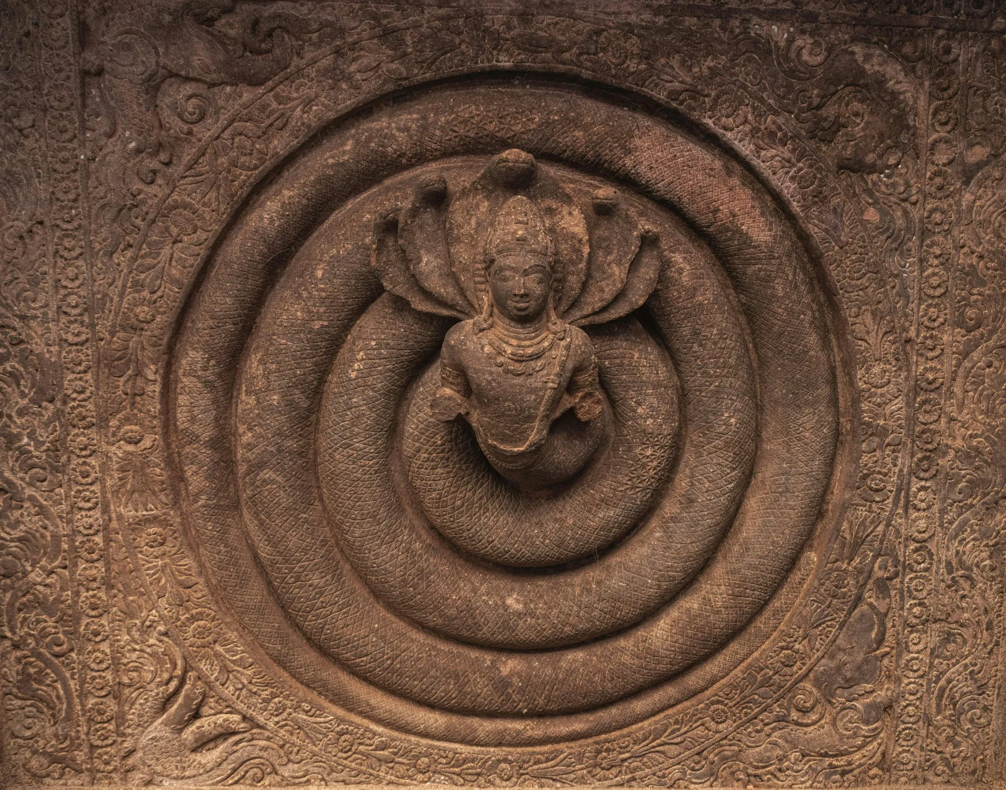 A carved stone deity under a many-headed serpent