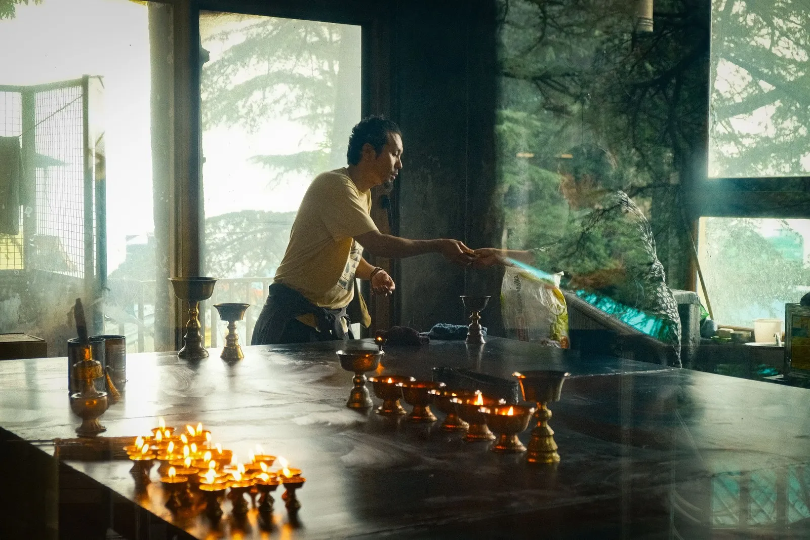 A man tending rows of butter lamps at a Buddhist temple in Dharamshala