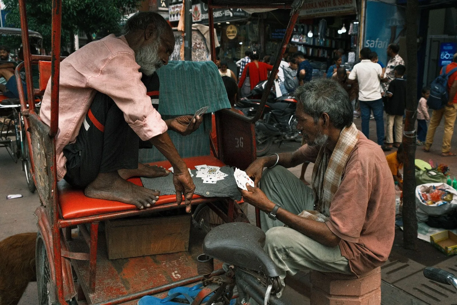 Two men playing cards on a cycle-rickshaw in a Delhi street