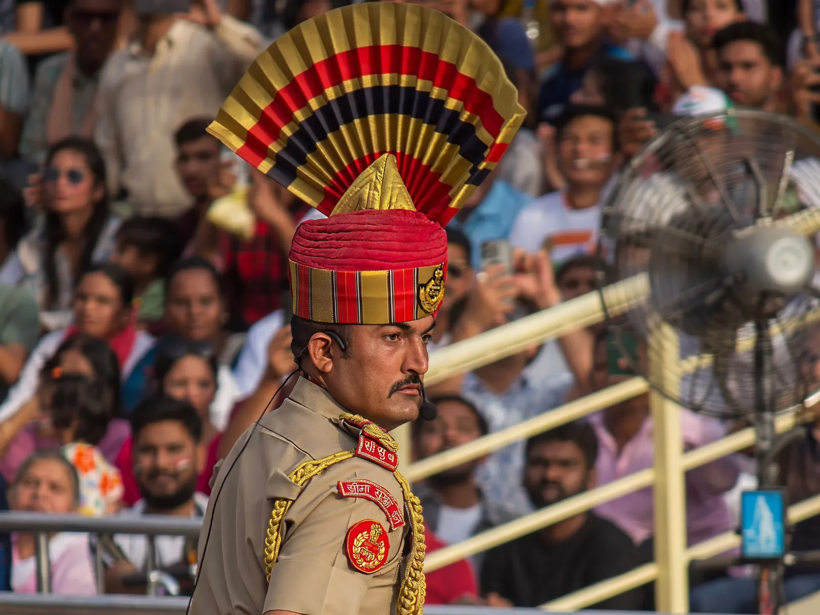 A Border Security Force guard mid-stride at the Wagah border ceremony, the stands full behind him