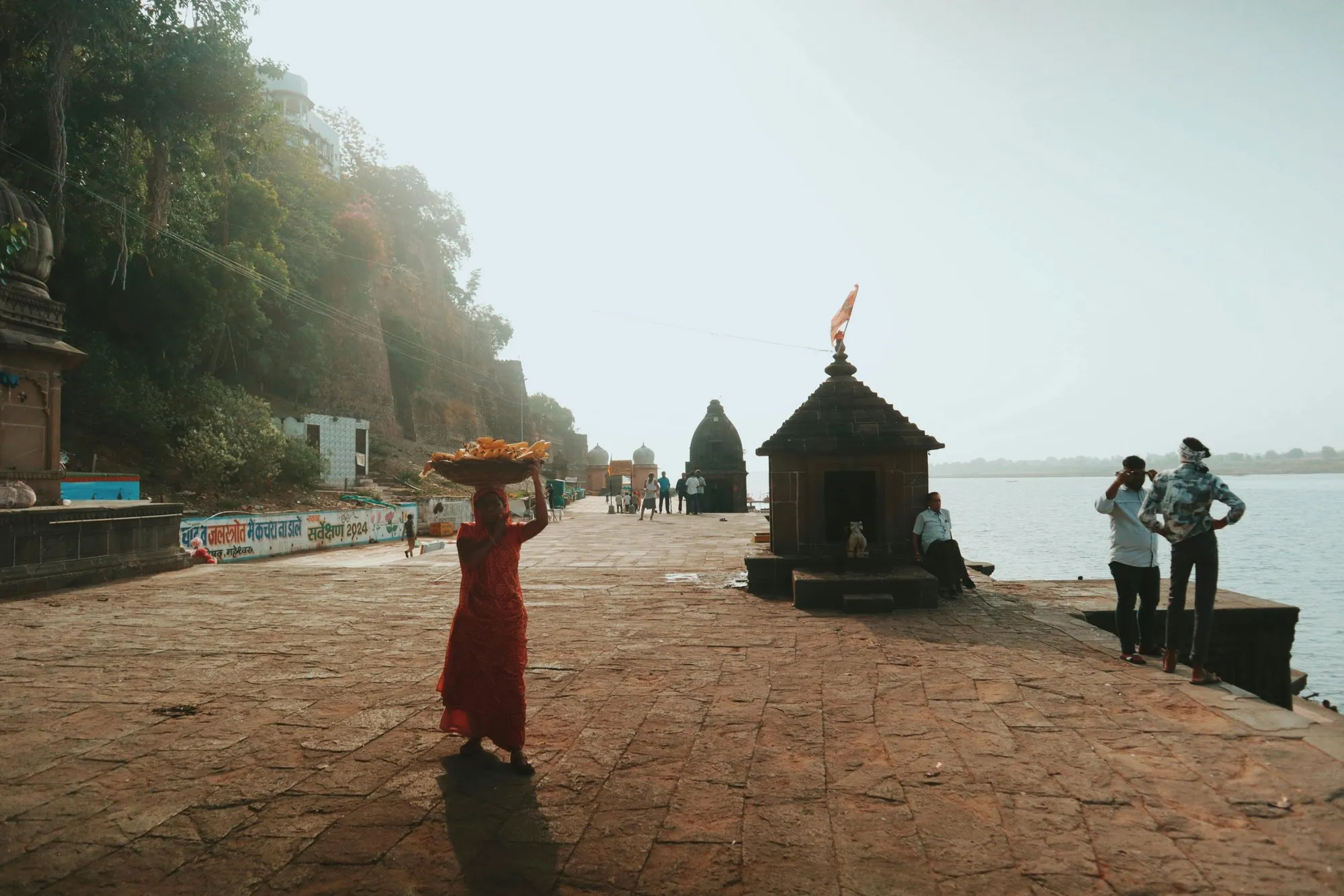 A woman carrying a basket along a river ghat
