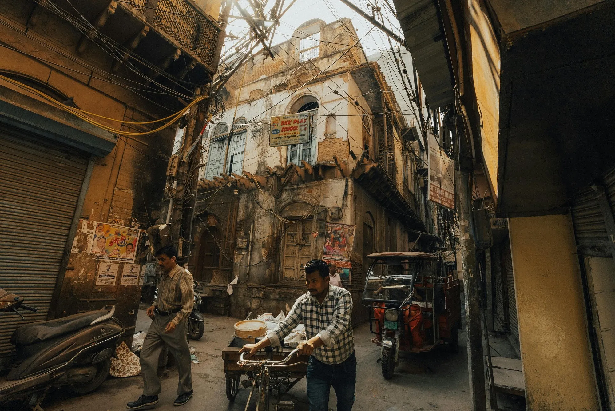 A cycle rickshaw and shoppers in an Old Delhi lane