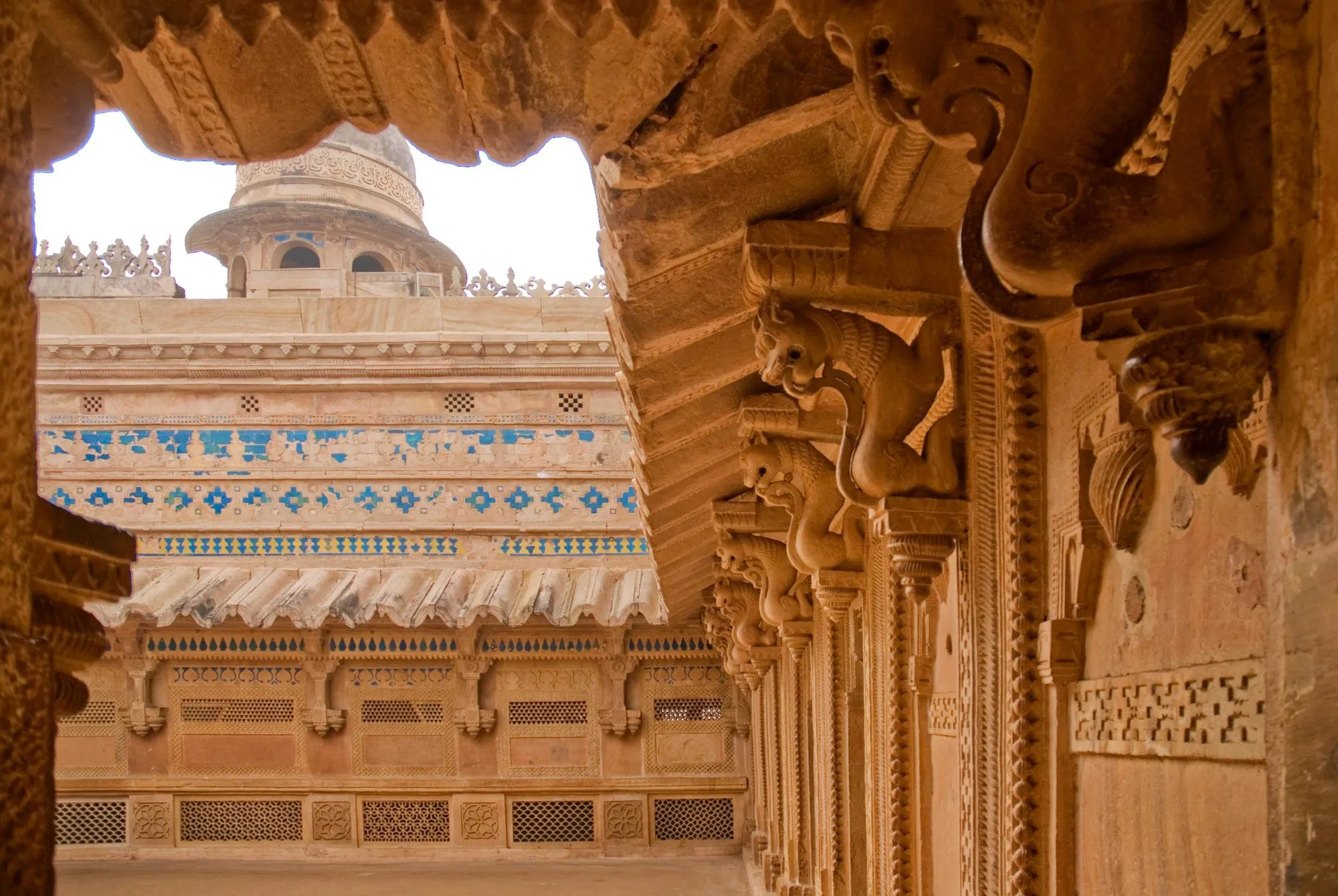 Blue tilework and carved sandstone seen through an arch