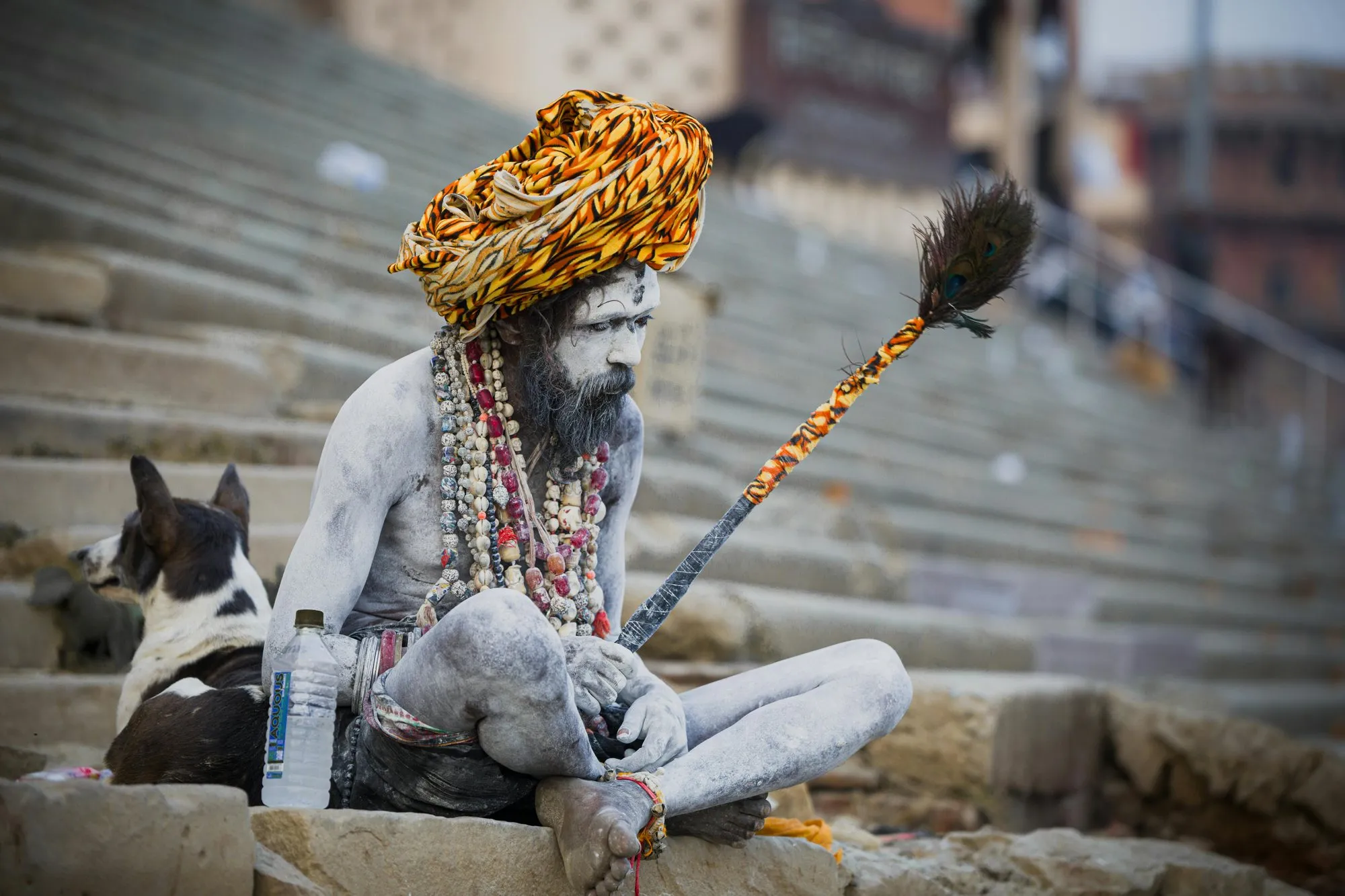 A sadhu in an orange turban with ash-covered skin on the ghats