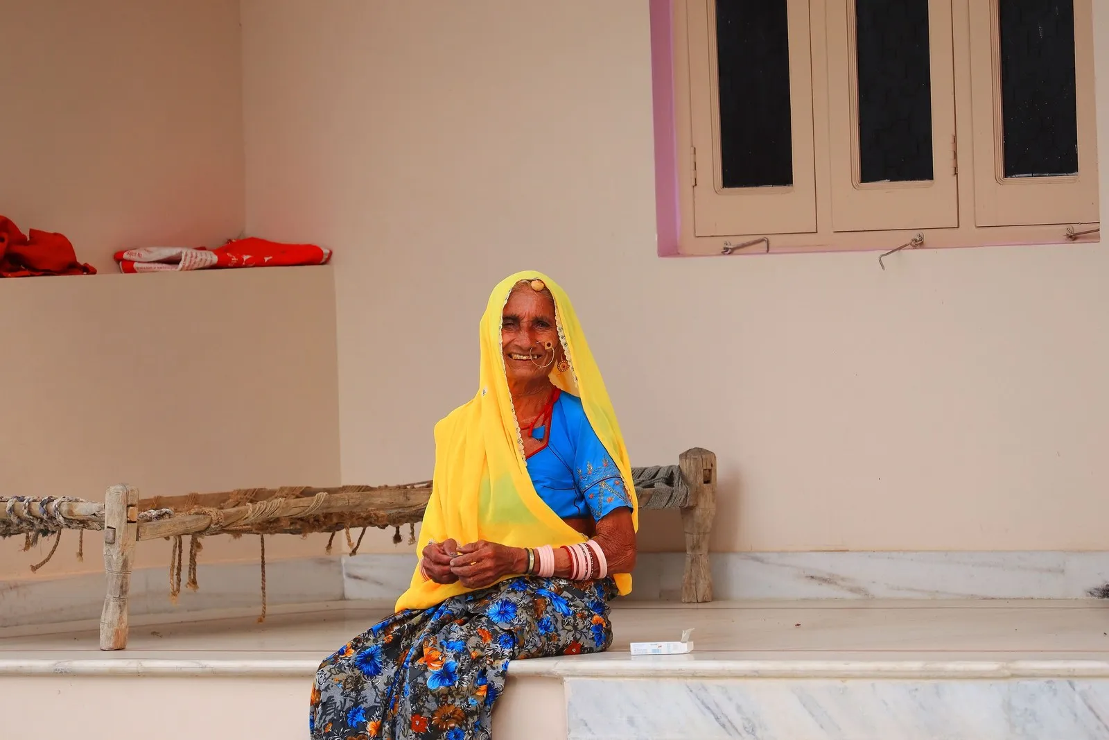 An elderly woman smiling outside her home in a village in Pali district, Rajasthan