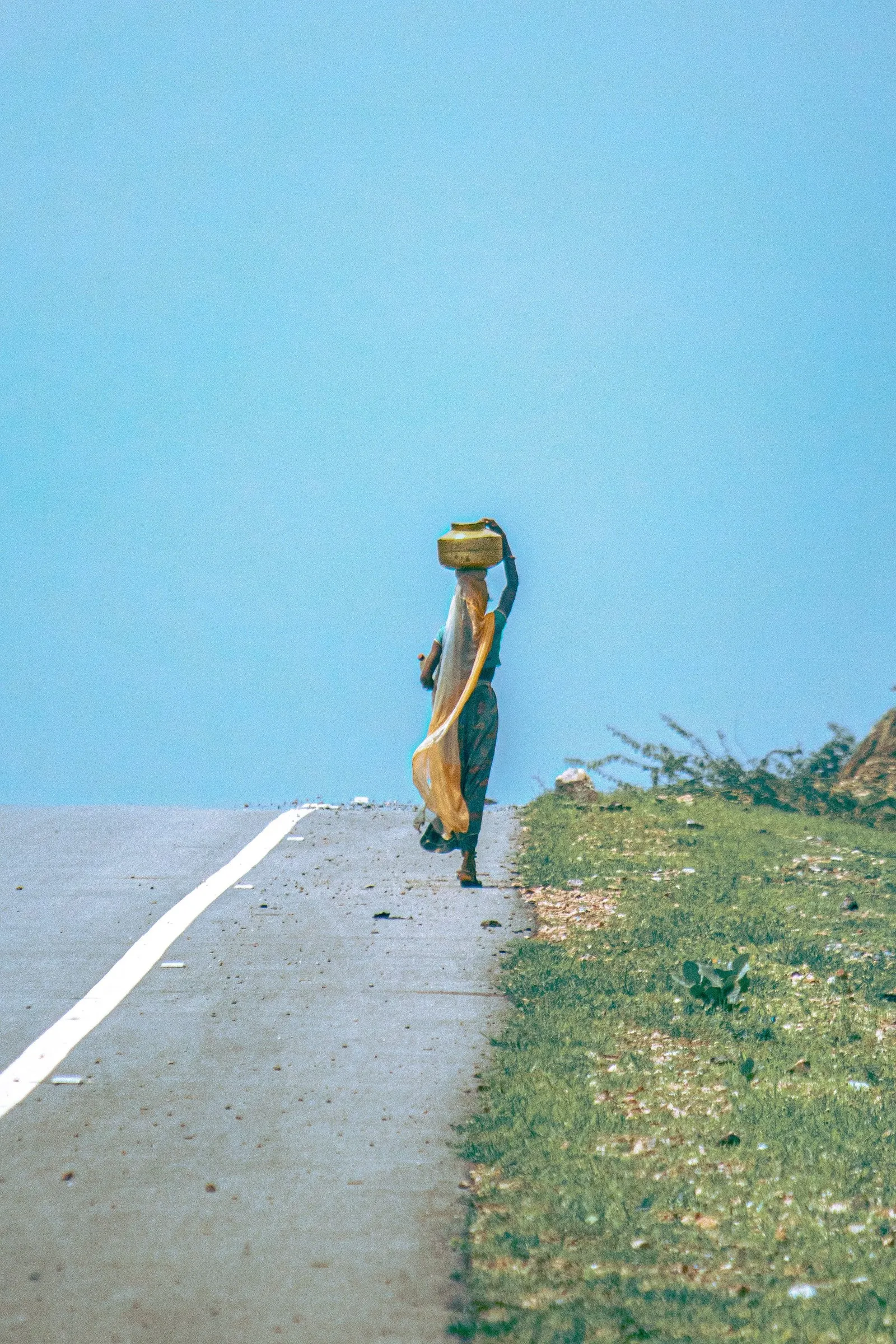 A woman carrying a water pot along a country road near Udaipur