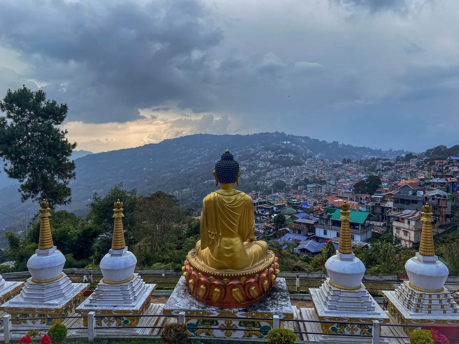A golden Buddha between white chortens above the town of Kalimpong