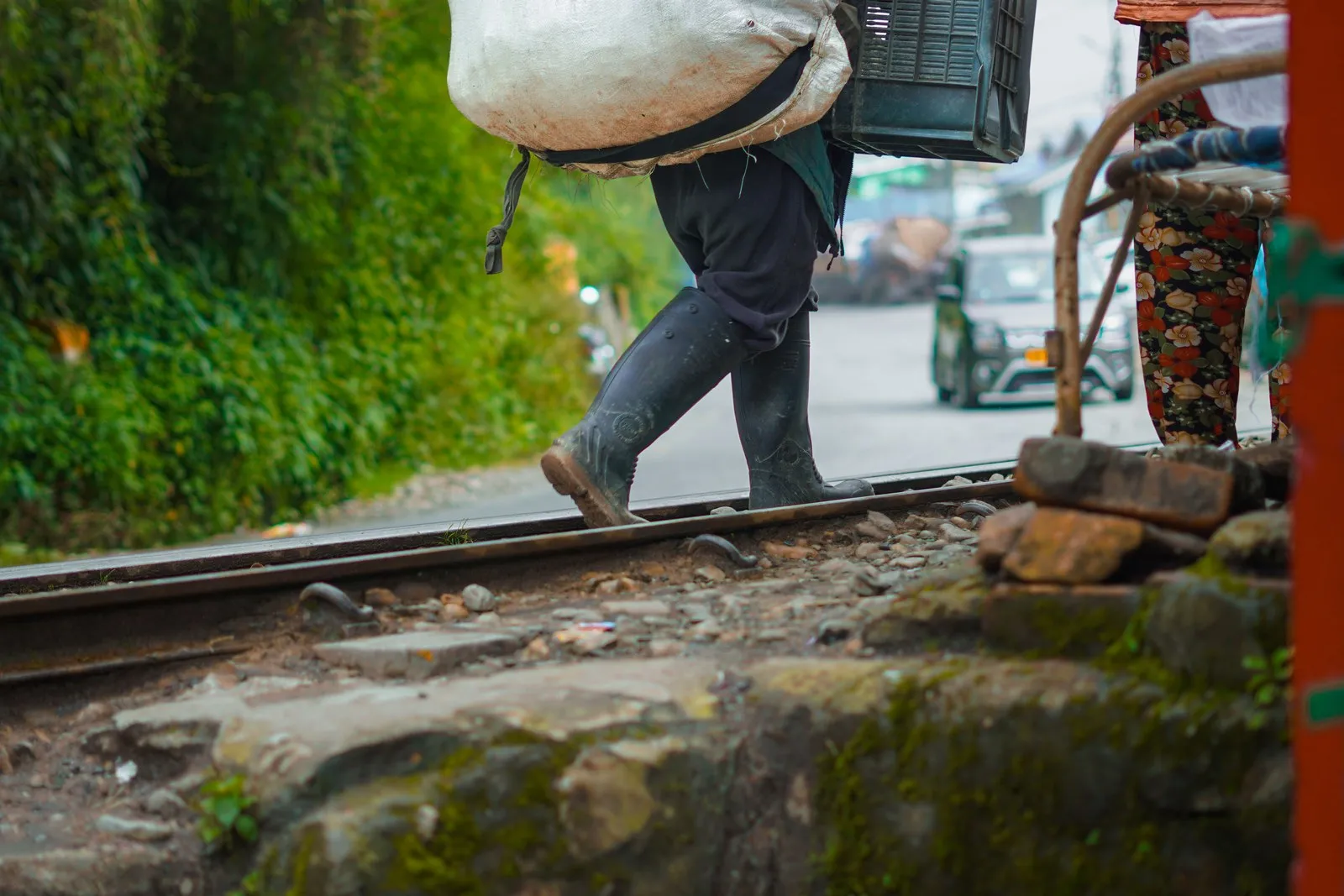 A porter in rubber boots carrying a load across the toy train’s tracks in Darjeeling