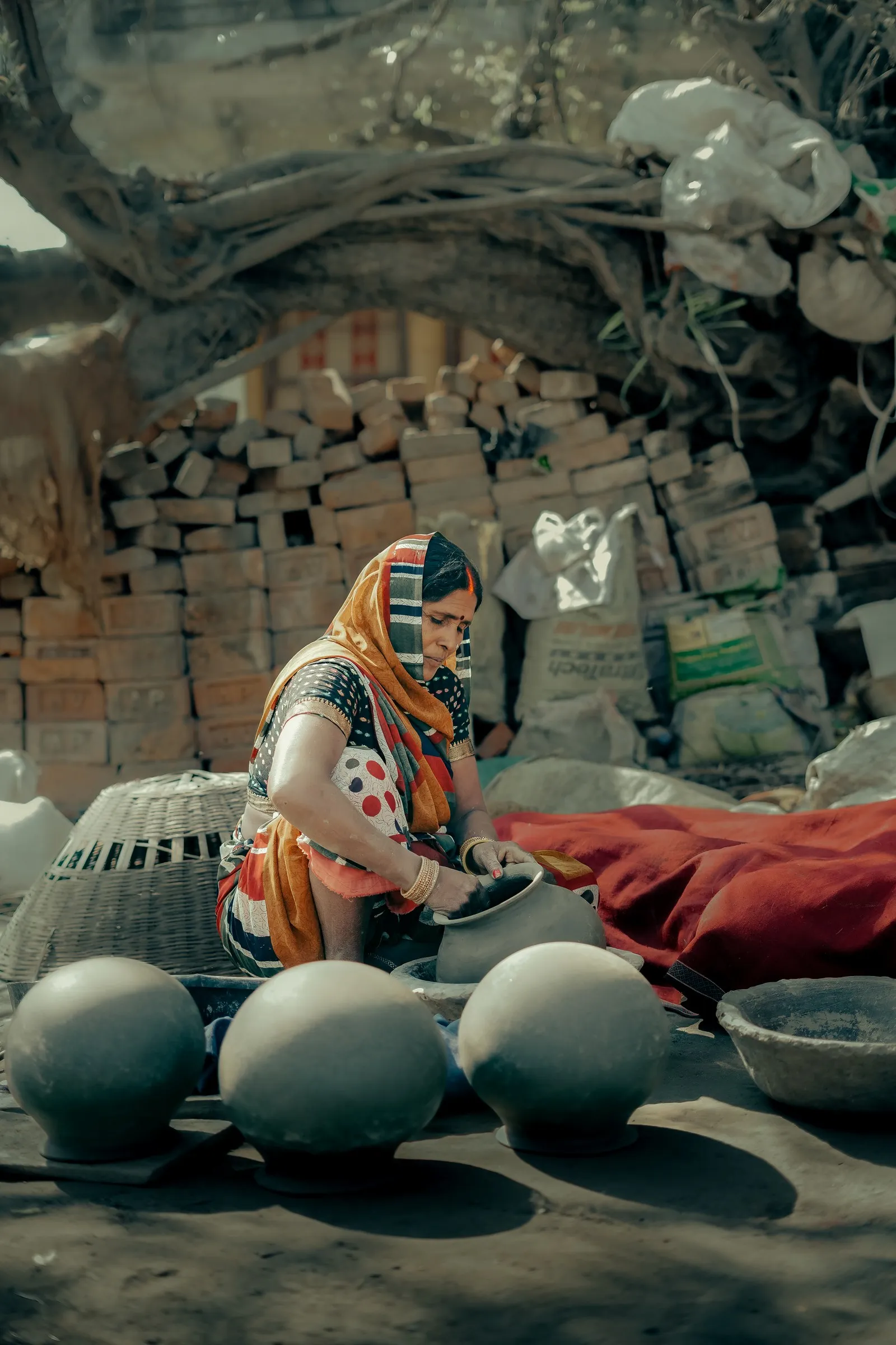 A woman shaping clay pots in a potter’s yard in Bihar