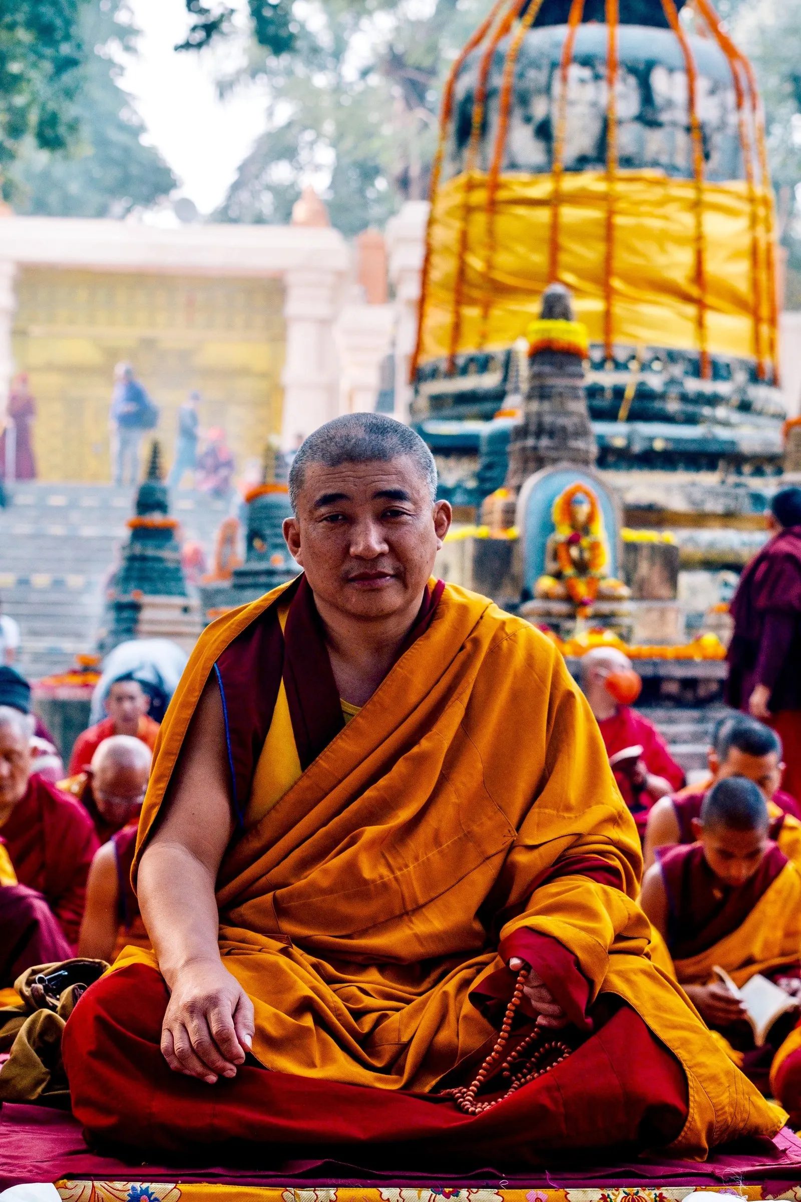 A Tibetan monk seated in prayer among other monks at the Mahabodhi temple, Bodh Gaya