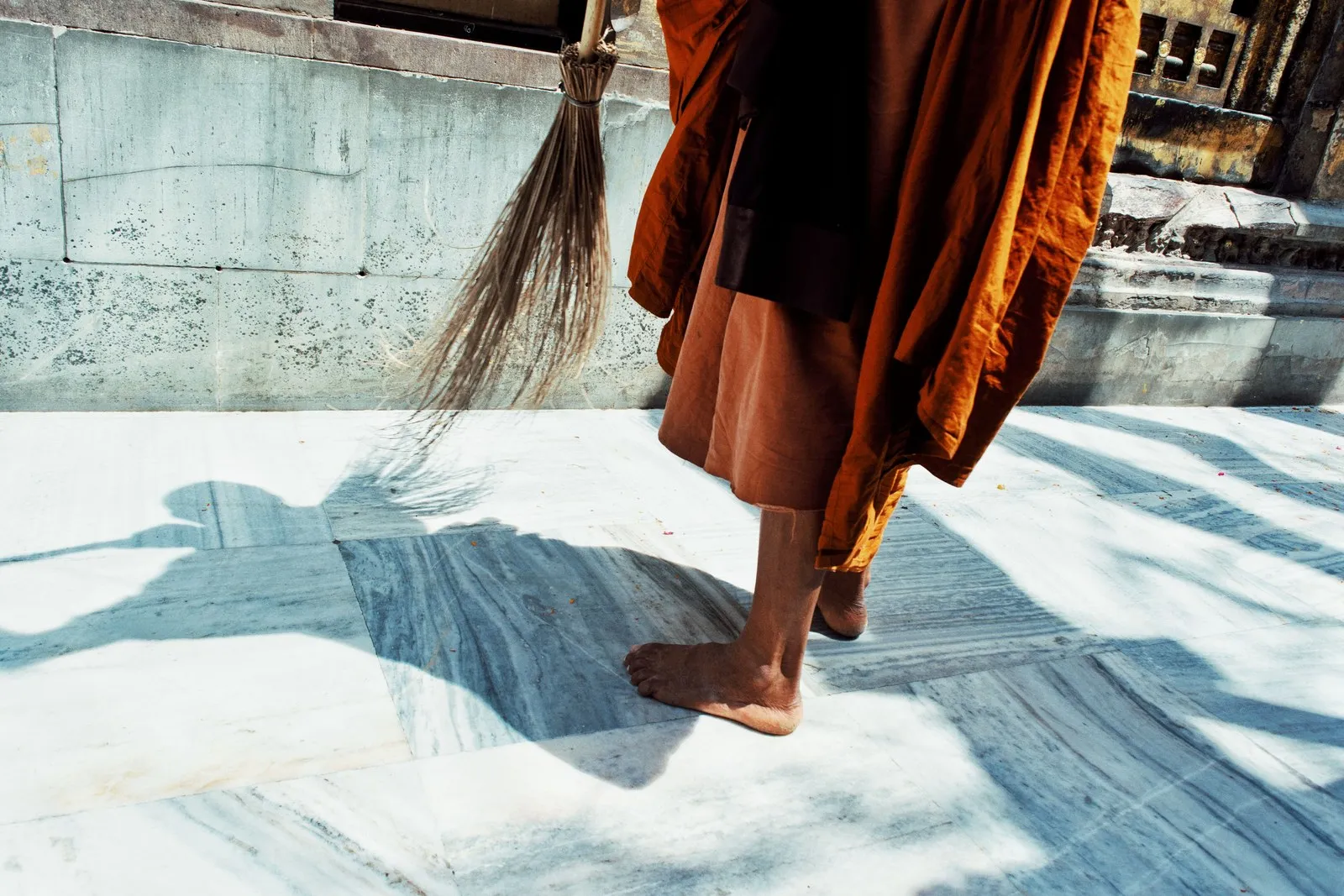 A monk sweeping the marble courtyard at Bodh Gaya