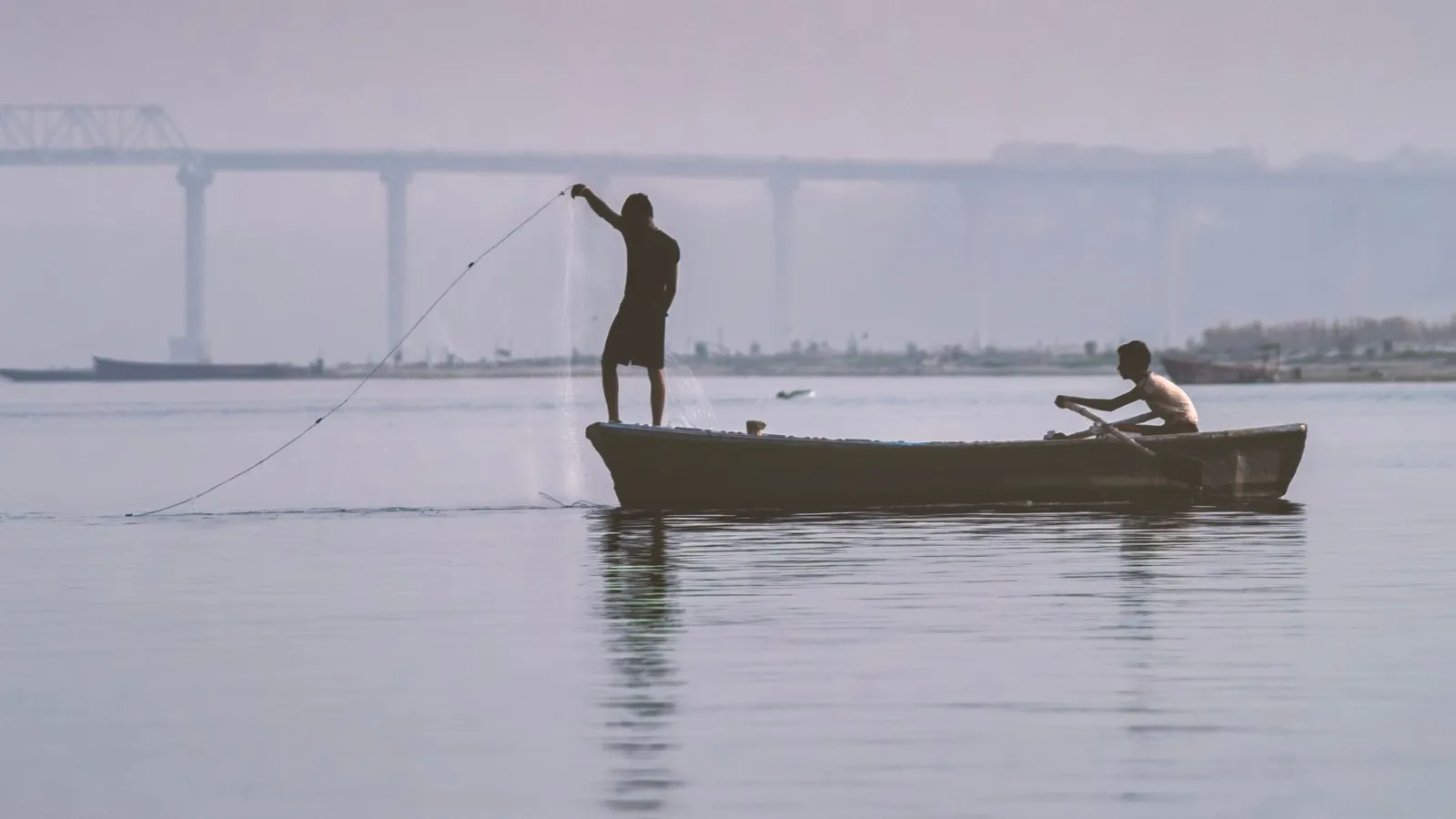 A fisherman casting his net from a boat on the Ganga at Varanasi