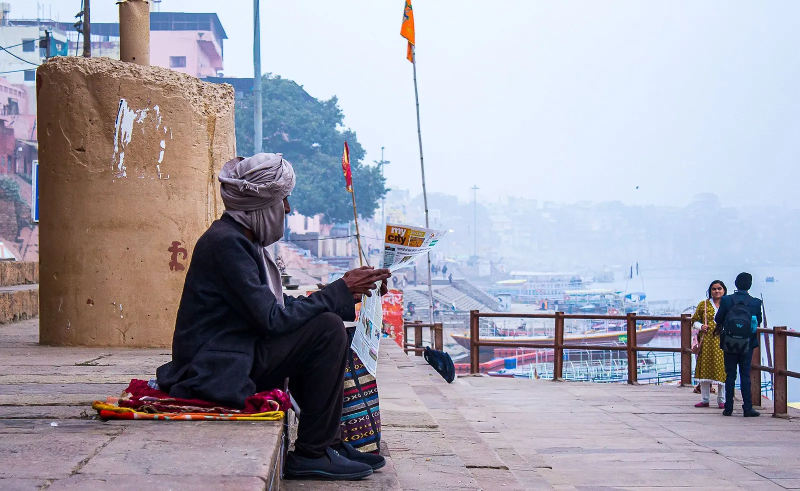 A man reading the morning paper on a ghat in the haze, Varanasi