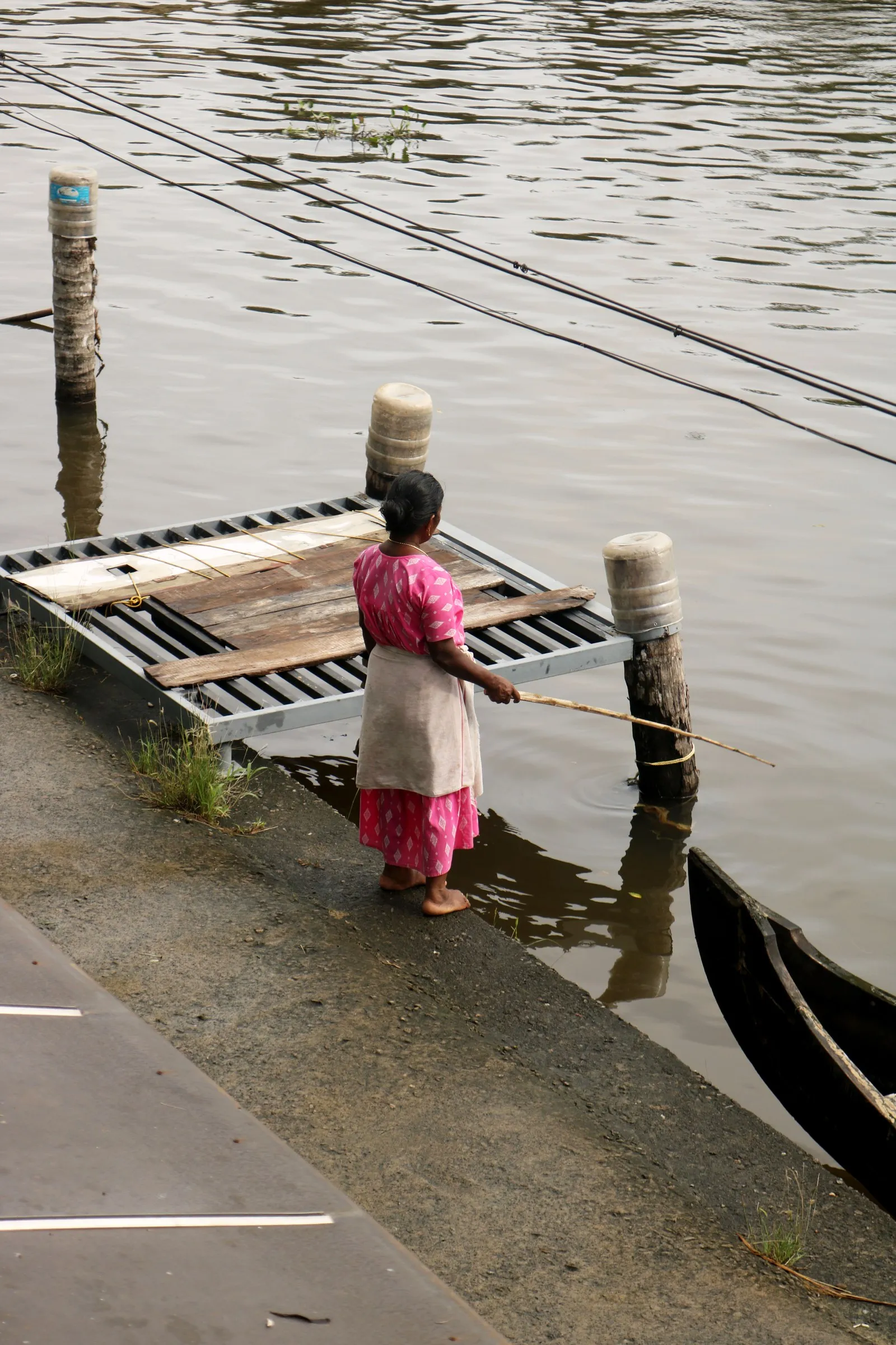 A woman fishing from the steps of a canal in Alappuzha