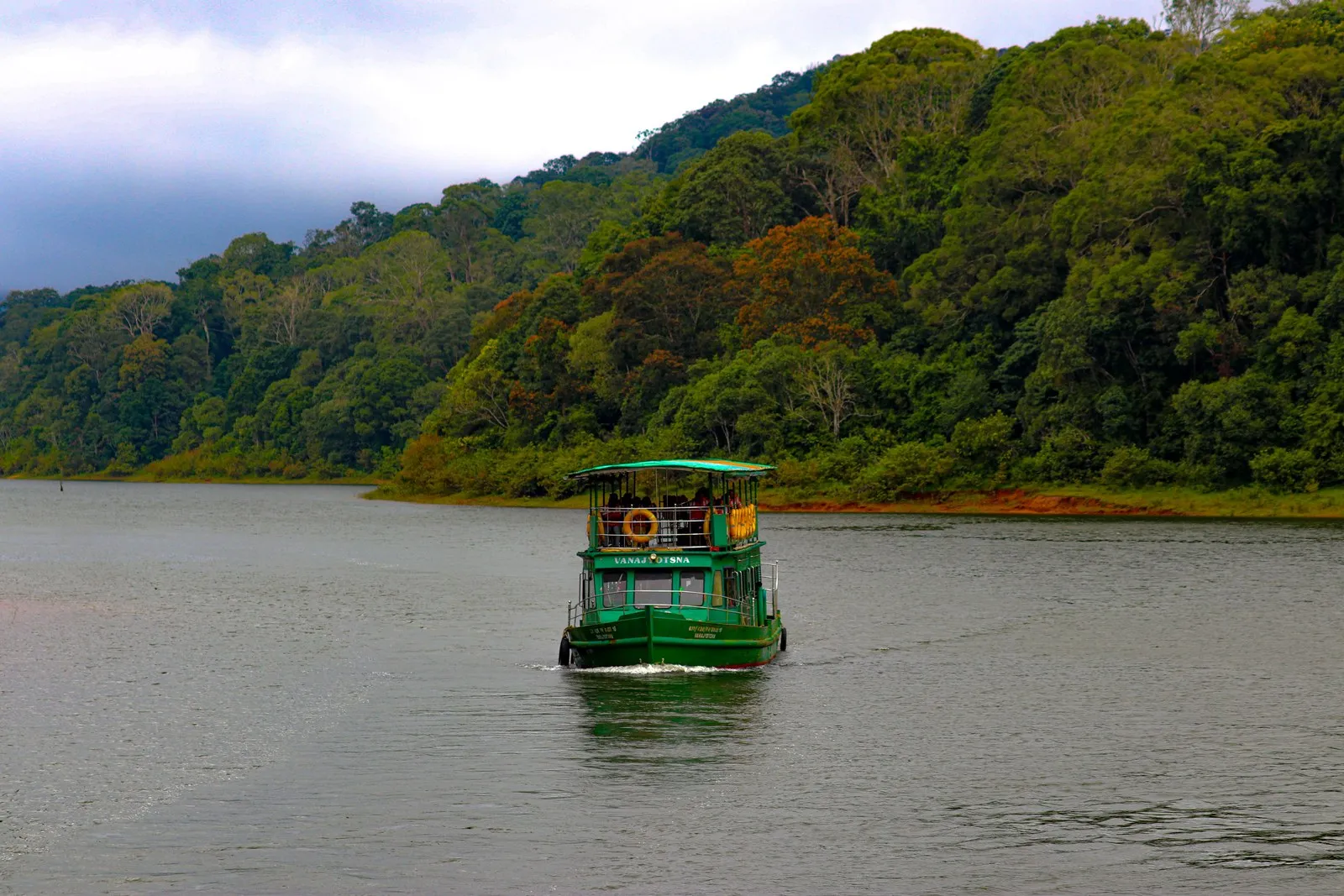 A boat on Periyar Lake between the forested hills, Thekkady