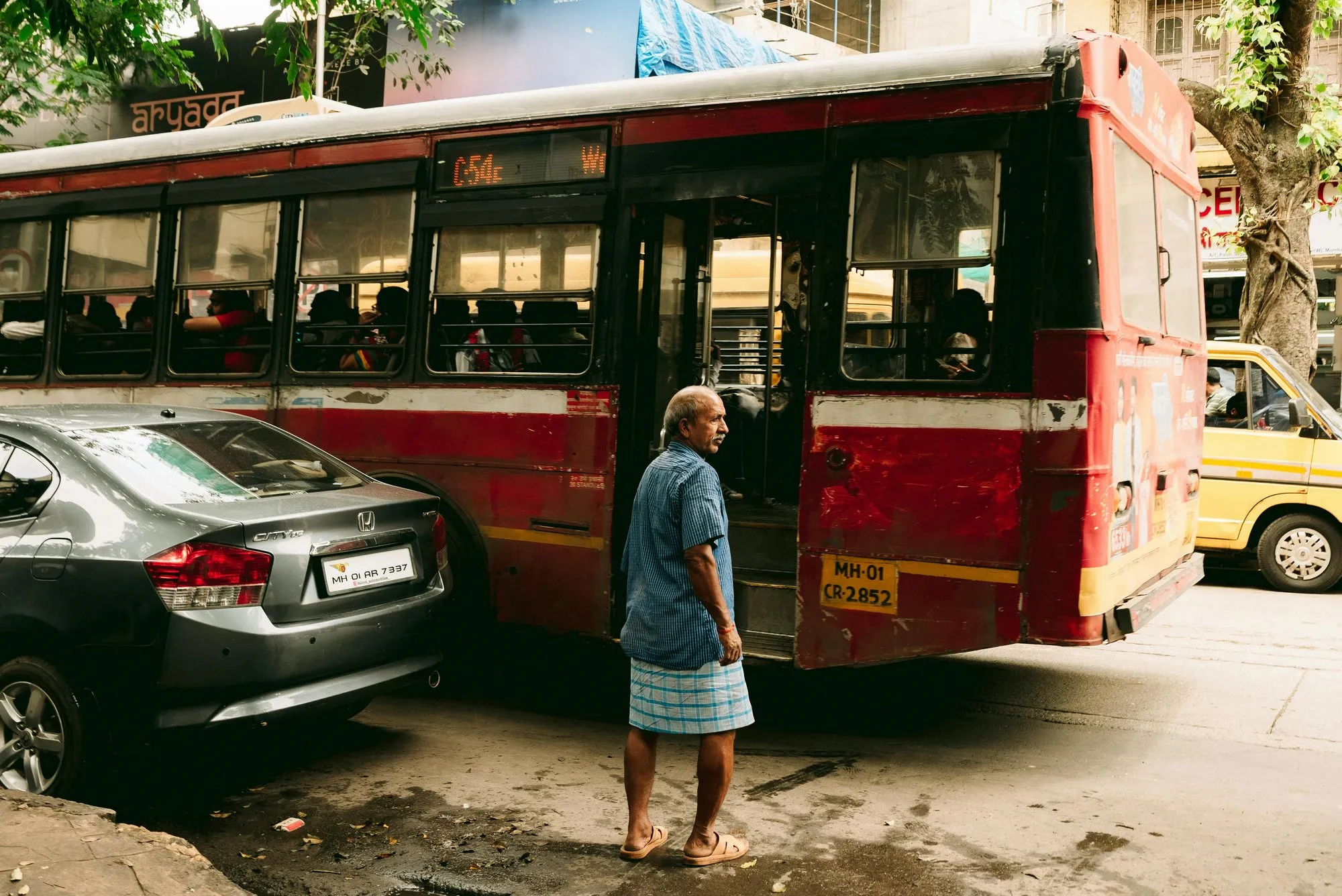 A man stepping off a red Mumbai bus