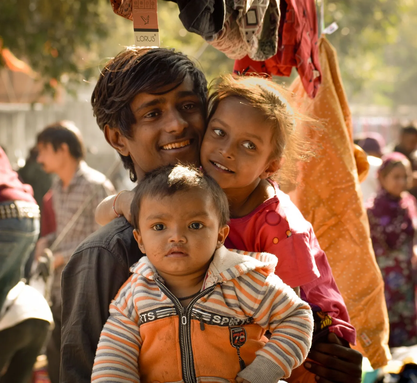 A young man with two children in a crowded Ahmedabad market