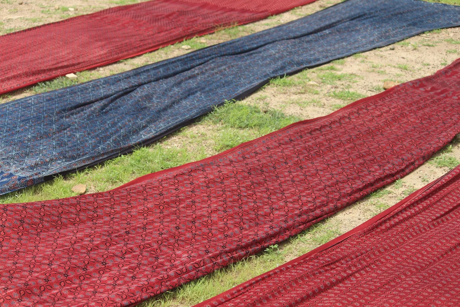 Lengths of red and indigo Ajrakh cloth laid out to dry on the grass at Ajrakhpur
