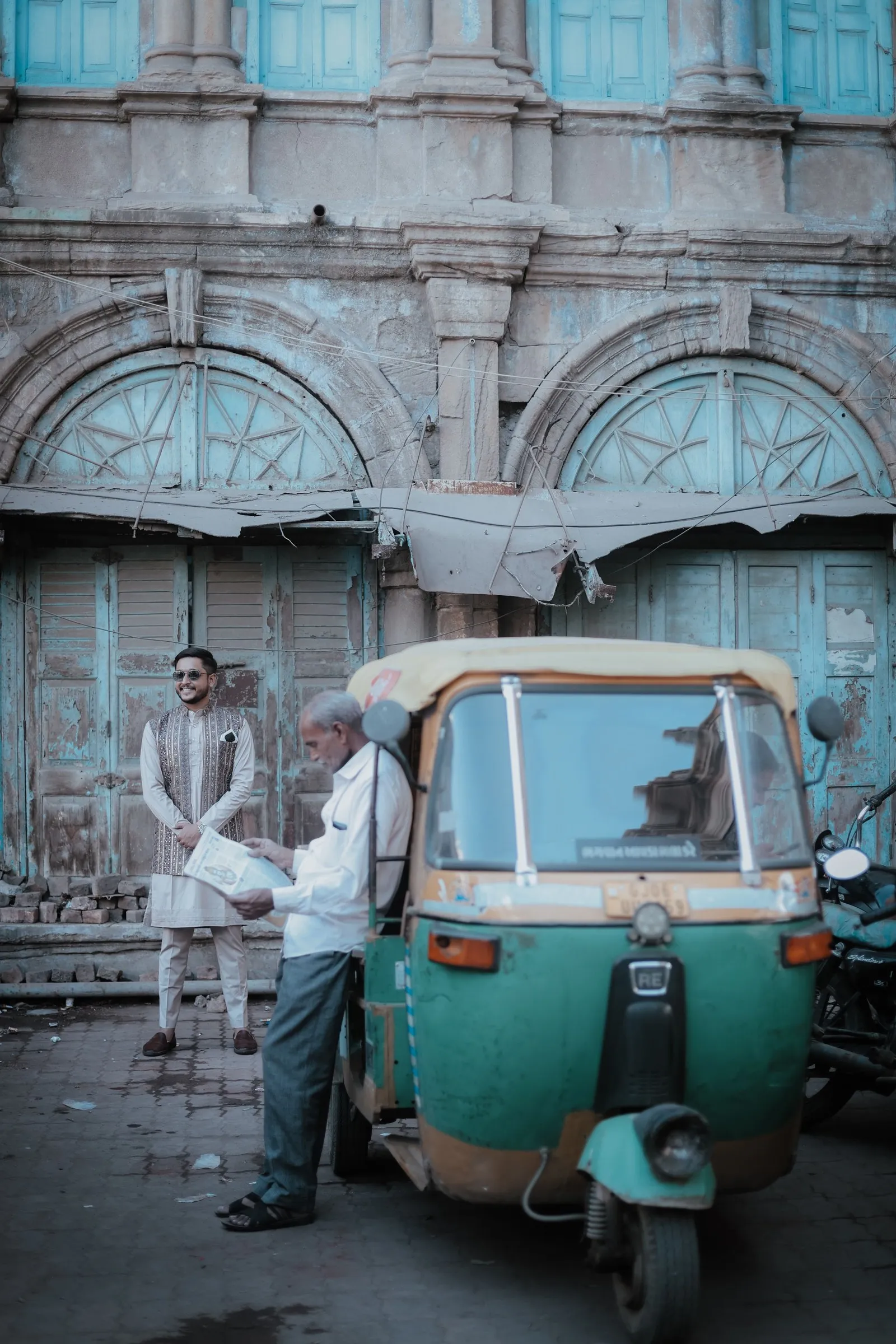 A man reading the paper beside an auto-rickshaw in the old city of Bhuj
