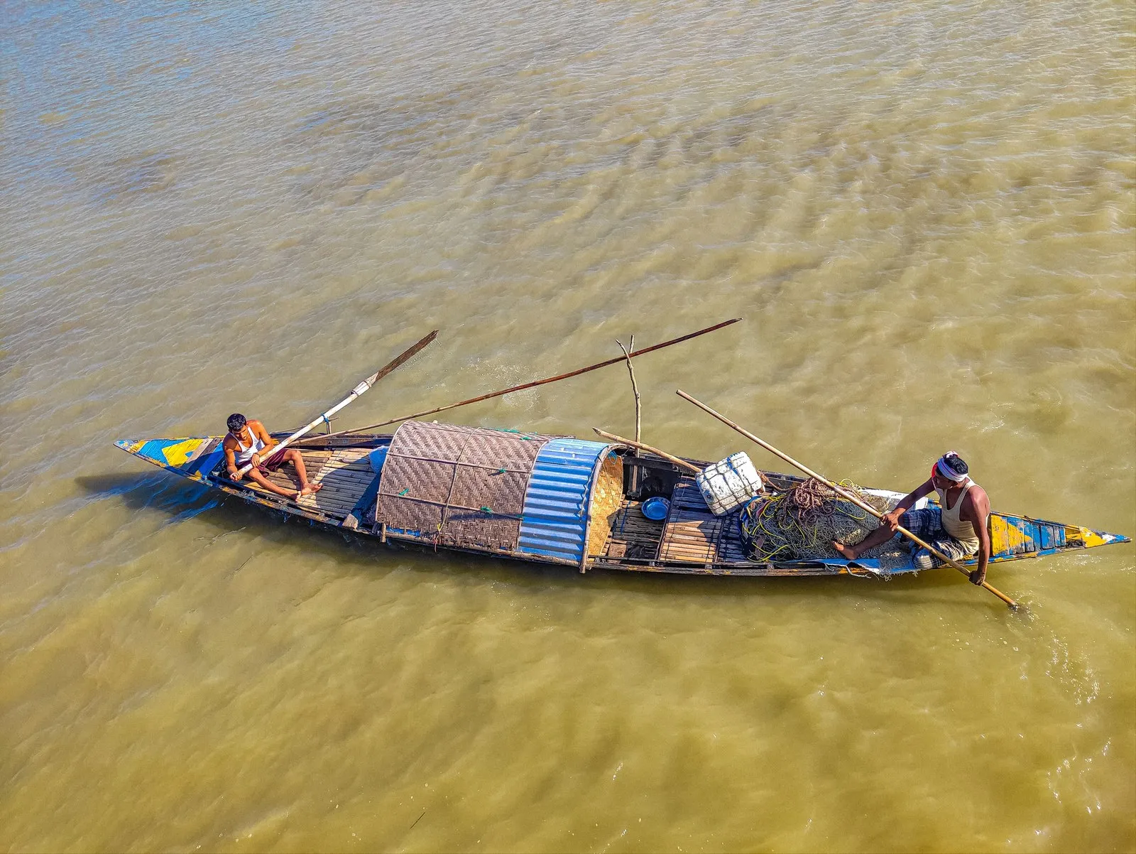 Fishermen poling a wooden boat across the Brahmaputra, Assam