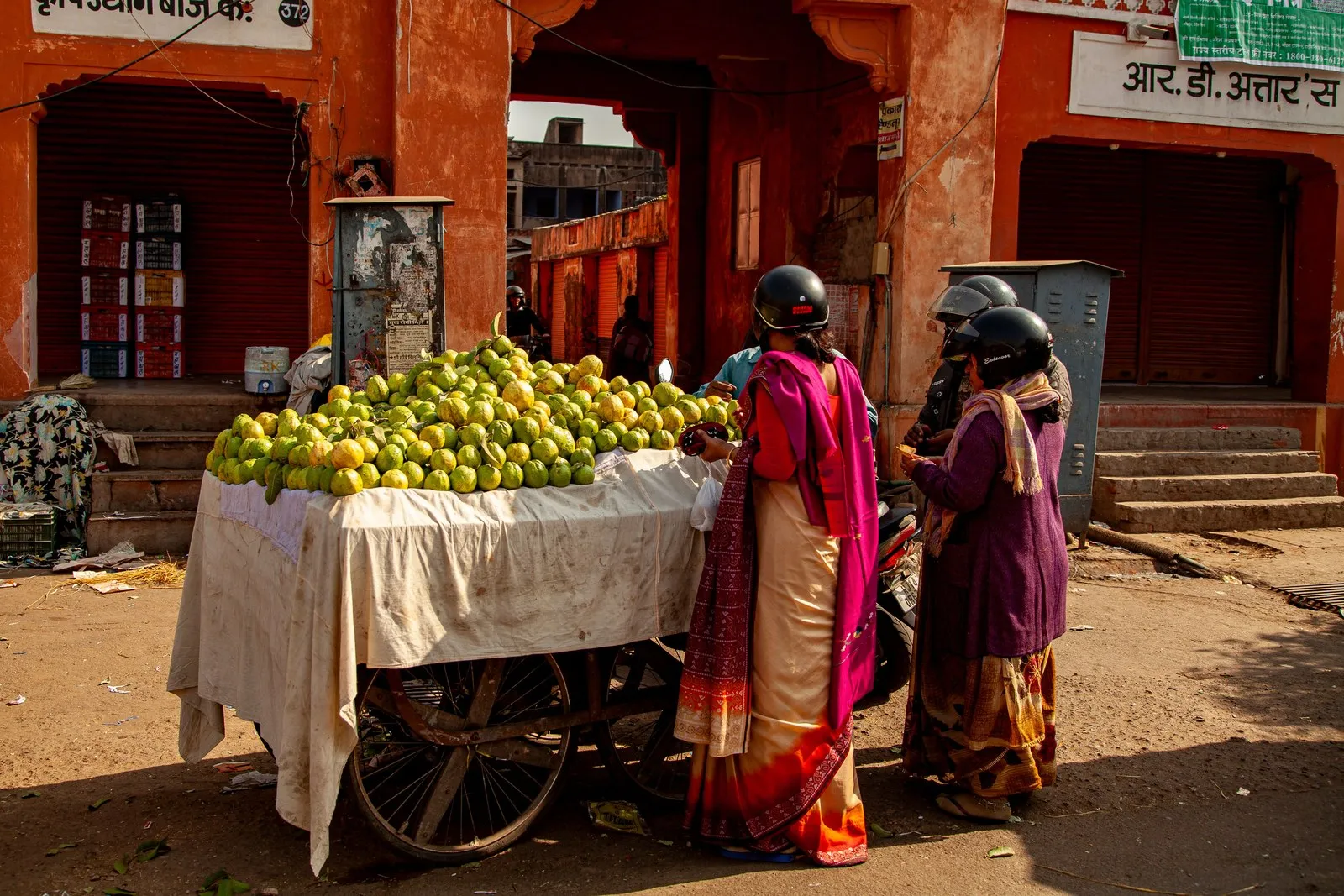 Women in saris buying guavas from a street cart in Jaipur
