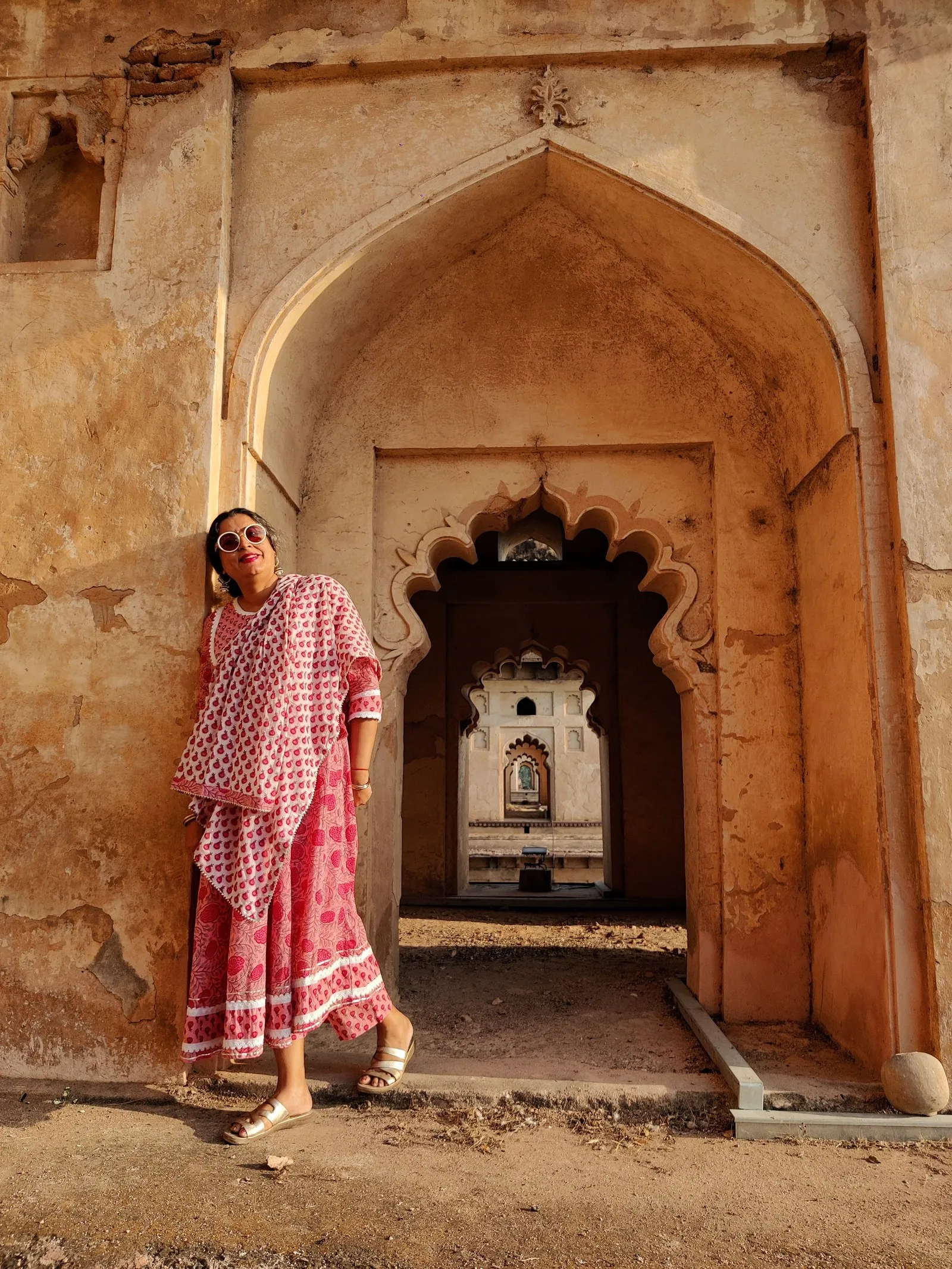 A woman in a pink sari standing in a carved archway at Orchha