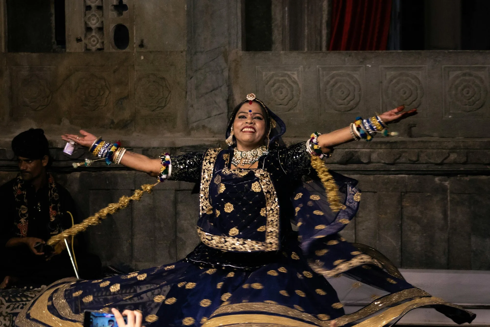 A Kalbelia dancer in black and silver, arms spread wide
