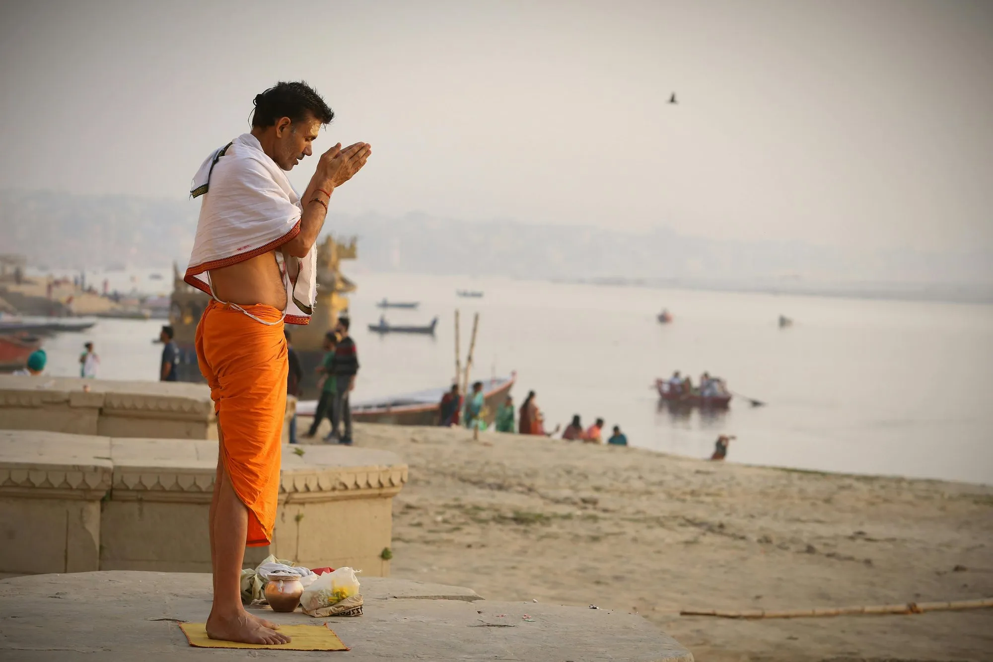 A man praying beside the Ganga at dawn