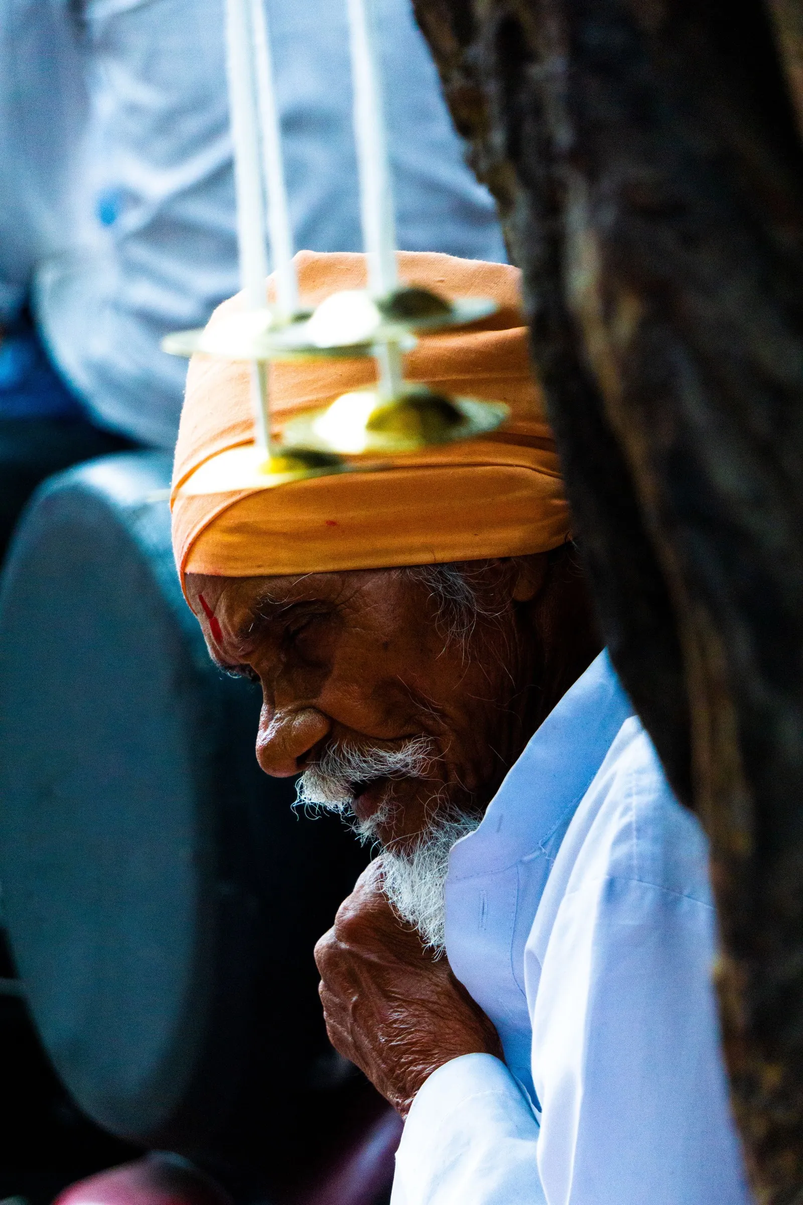 An elderly man in a saffron turban, eyes closed in prayer, Haridwar