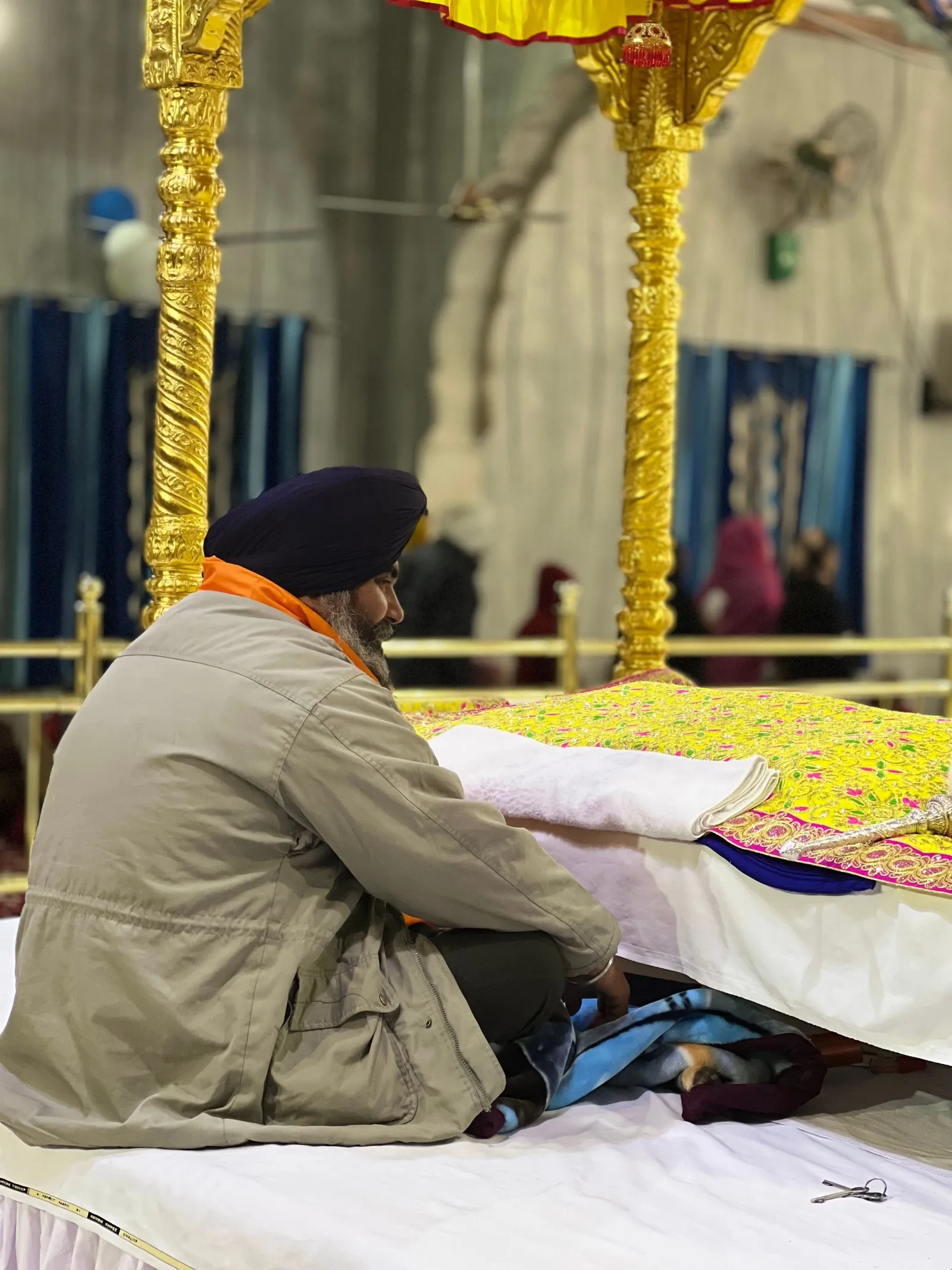 A Sikh man in prayer beside a gilded canopy in the Golden Temple, Amritsar