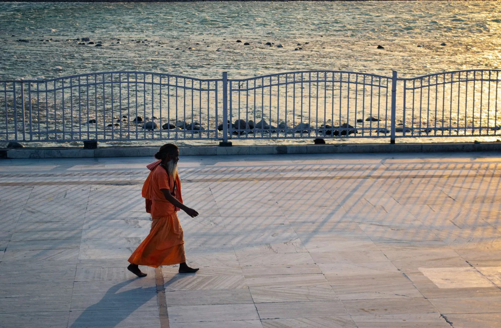 A sadhu in saffron walking the riverside at dusk, Rishikesh